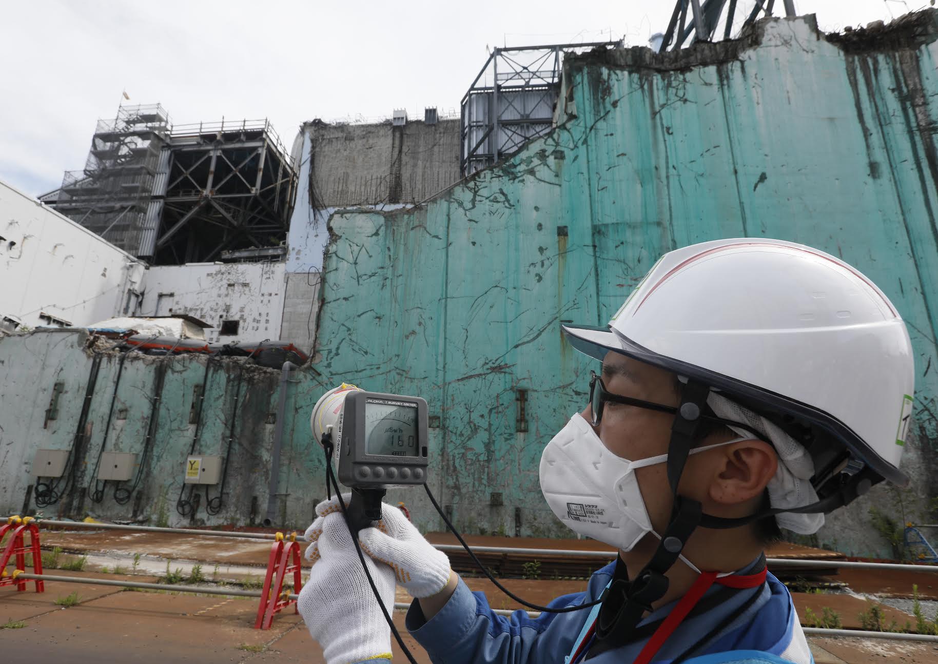 In this picture taken on July 27, 2018, a staff member of the Tokyo Electric Power Company measures radiation levels between reactor unit 2 and unit 3 (Rear) at the tsunami-crippled Tokyo Electric Power Company Fukushima Dai-ichi nuclear power plant in Okuma, Fukushima prefecture. (Kimimasa Mayama—KAFP/Getty Images)