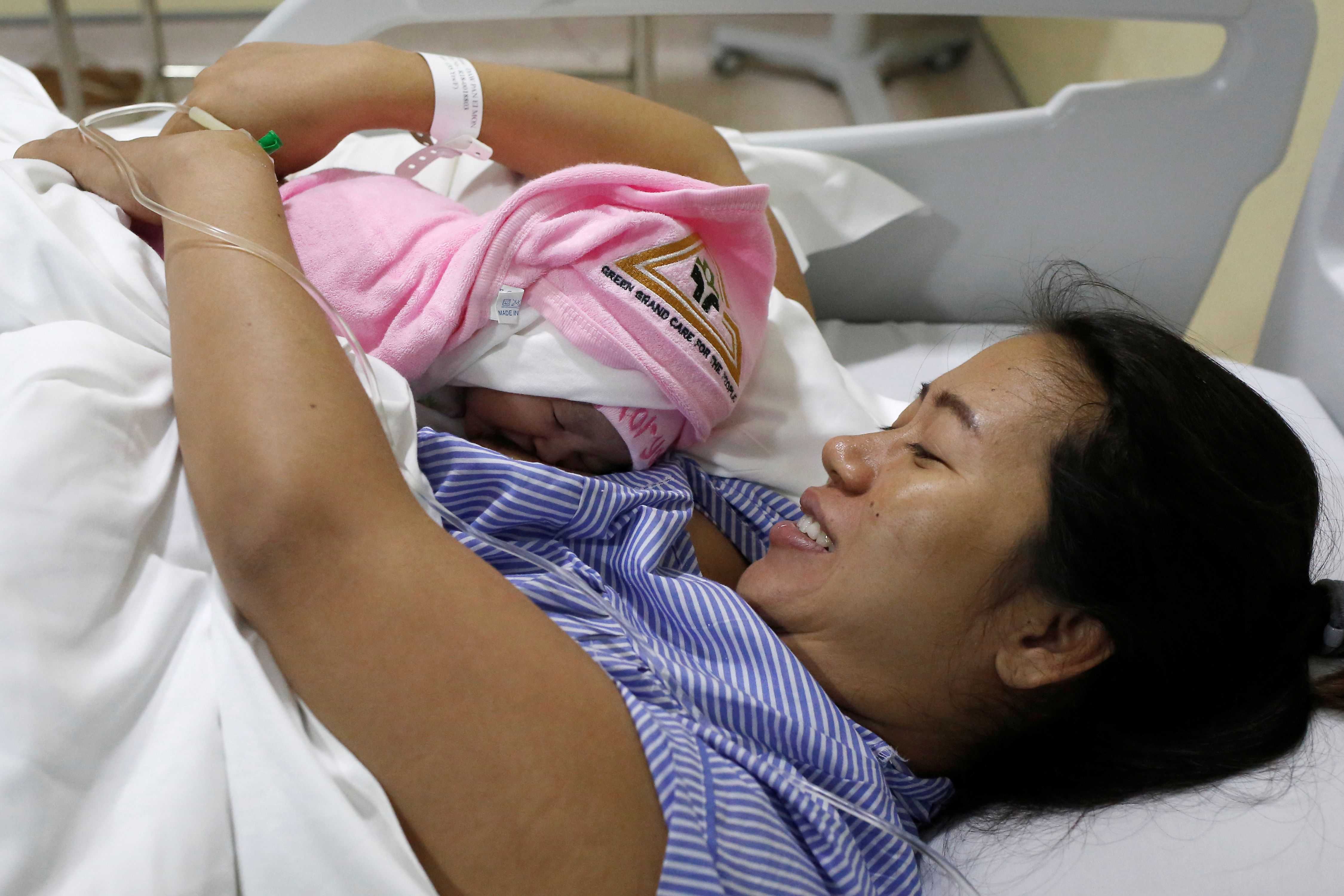 Pan Ei Mon, the wife of detained Reuters journalist Wa Lone, embraces her newborn baby girl Thet Htar Angel in her hospital room in Yangon on Aug. 10, 2018. (Ann Wang—AFP/Getty Images)