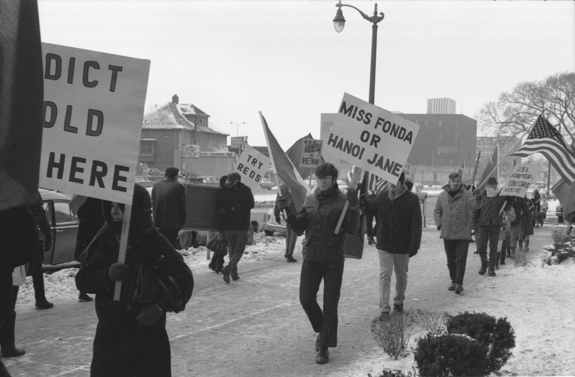 Protesters carrying signs protesting Jane Fonda's visit to Hanoi outside Howard Johnson's Hotel in Detroit during the time of the 