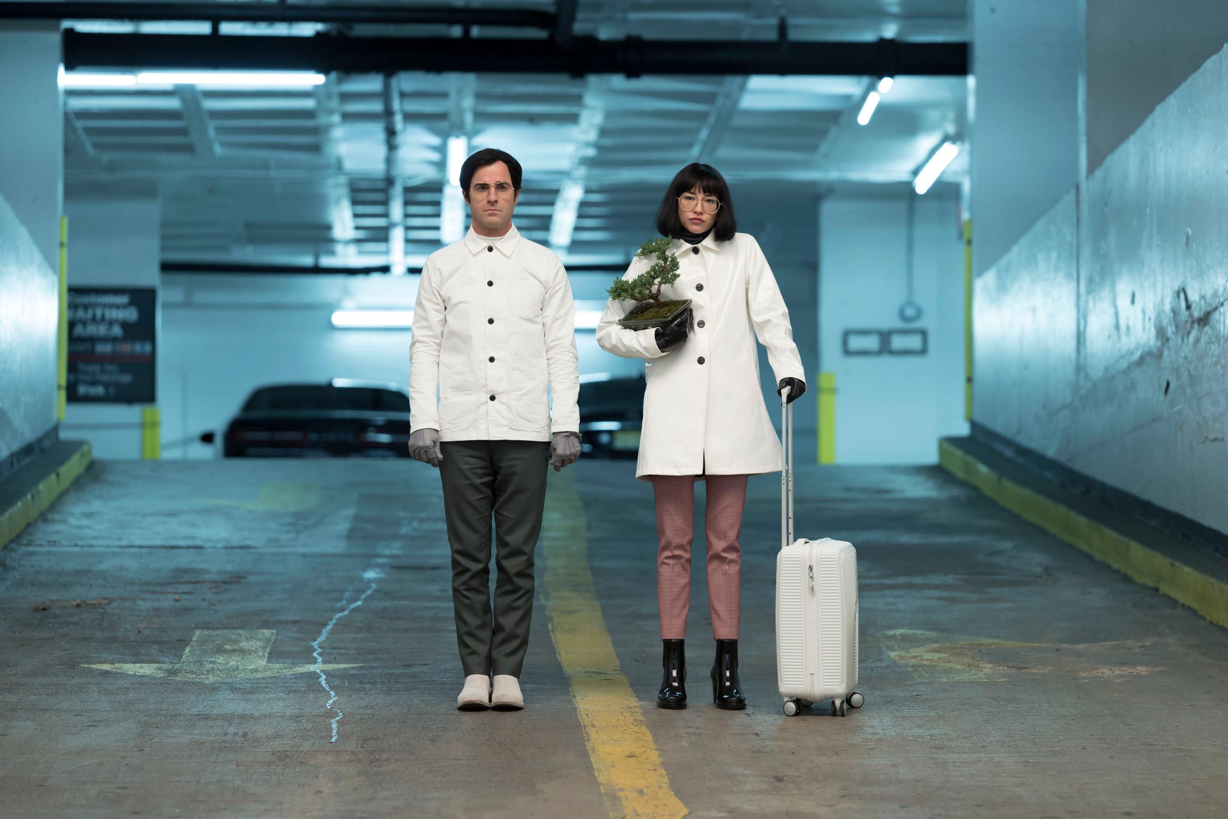 Justin Theroux and Sonoya Mizuno stand in front of a car