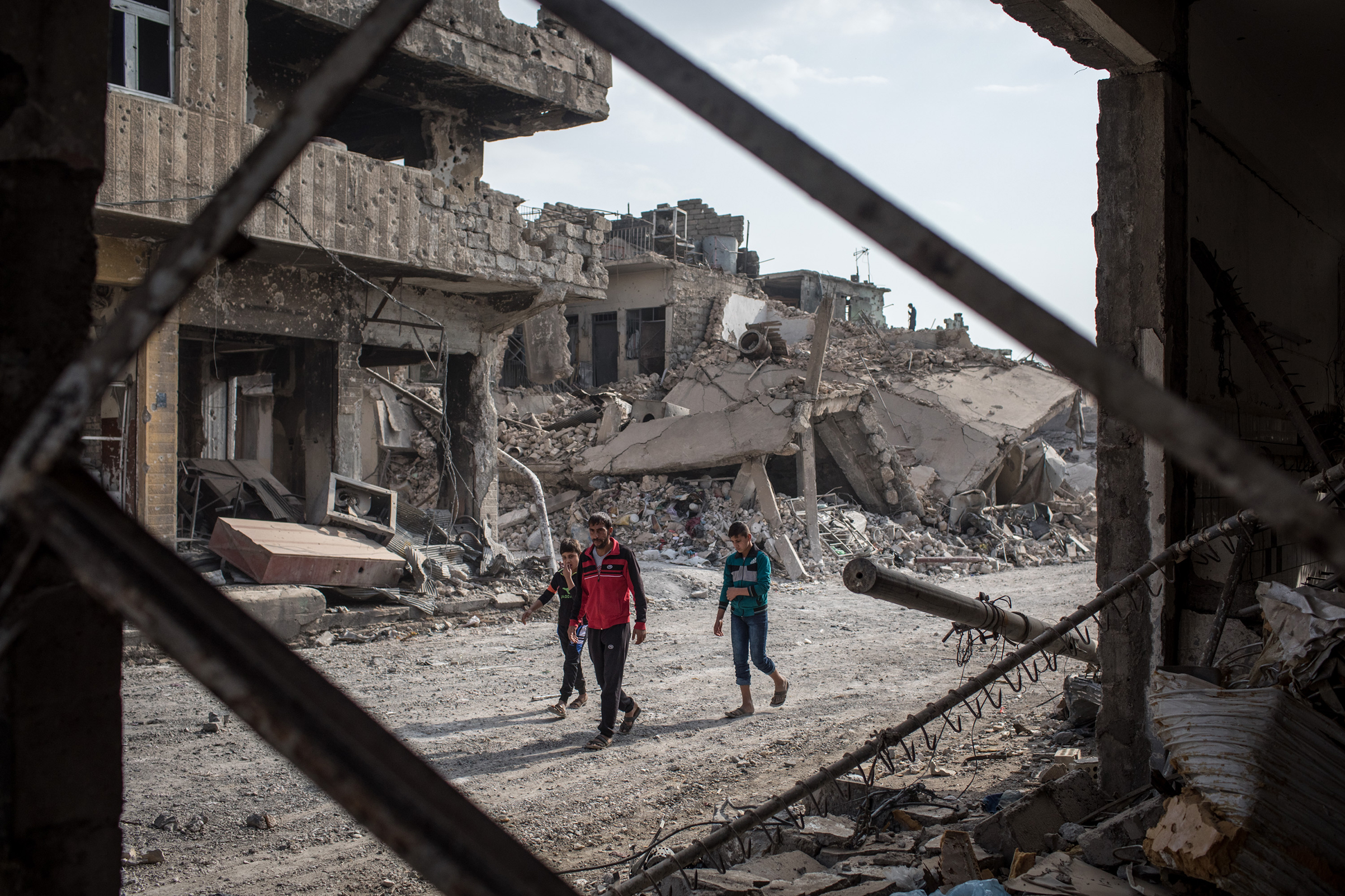 People walk amongst rubble from destroyed buildings in an outer neighborhood of the Old City in West Mosul on November 6, 2017 in Mosul, Iraq. (Chris McGrath—Getty Images)