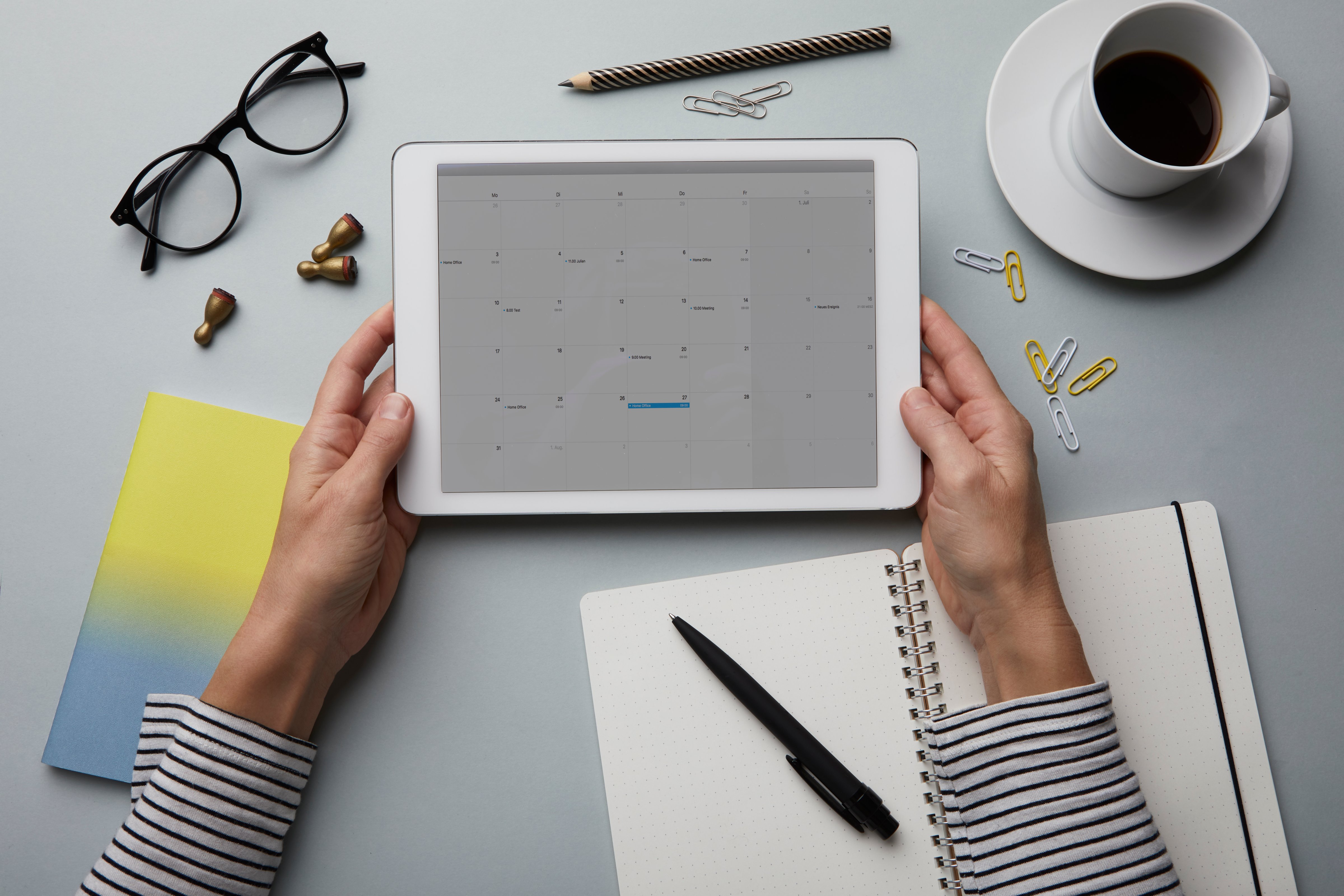 Woman holding tablet with calendar on desk
