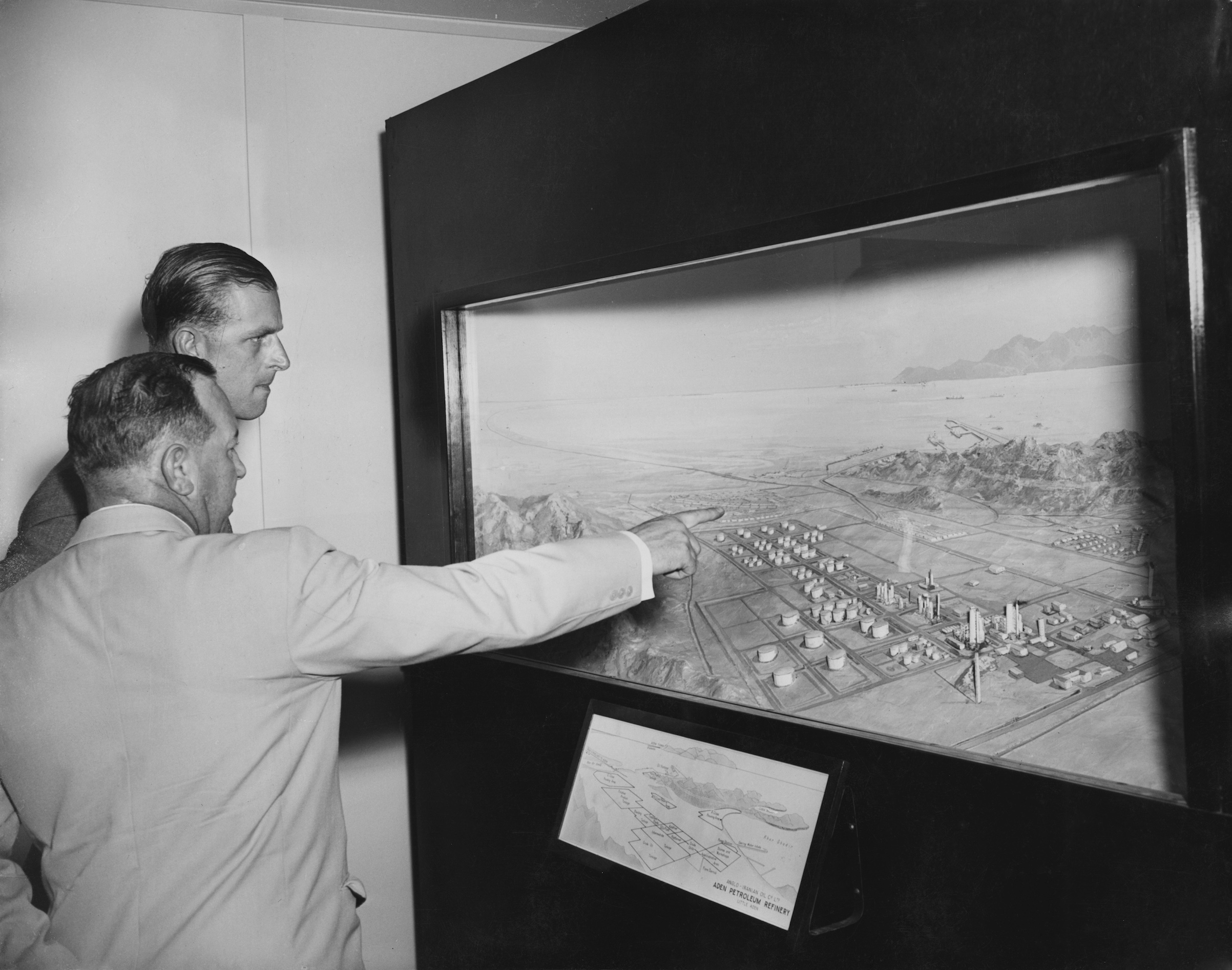 Prince Philip, Duke of Edinburgh visits the Aden Petroleum Refinery, an Anglo-Iranian Oil Company refinery at Little Aden during a Commonwealth visit to Yemen, April 27,1954. Here he is shown a panoramic model of the refinery by General Manager A. W. G. Trantor. (William Vanderson/Getty Images)