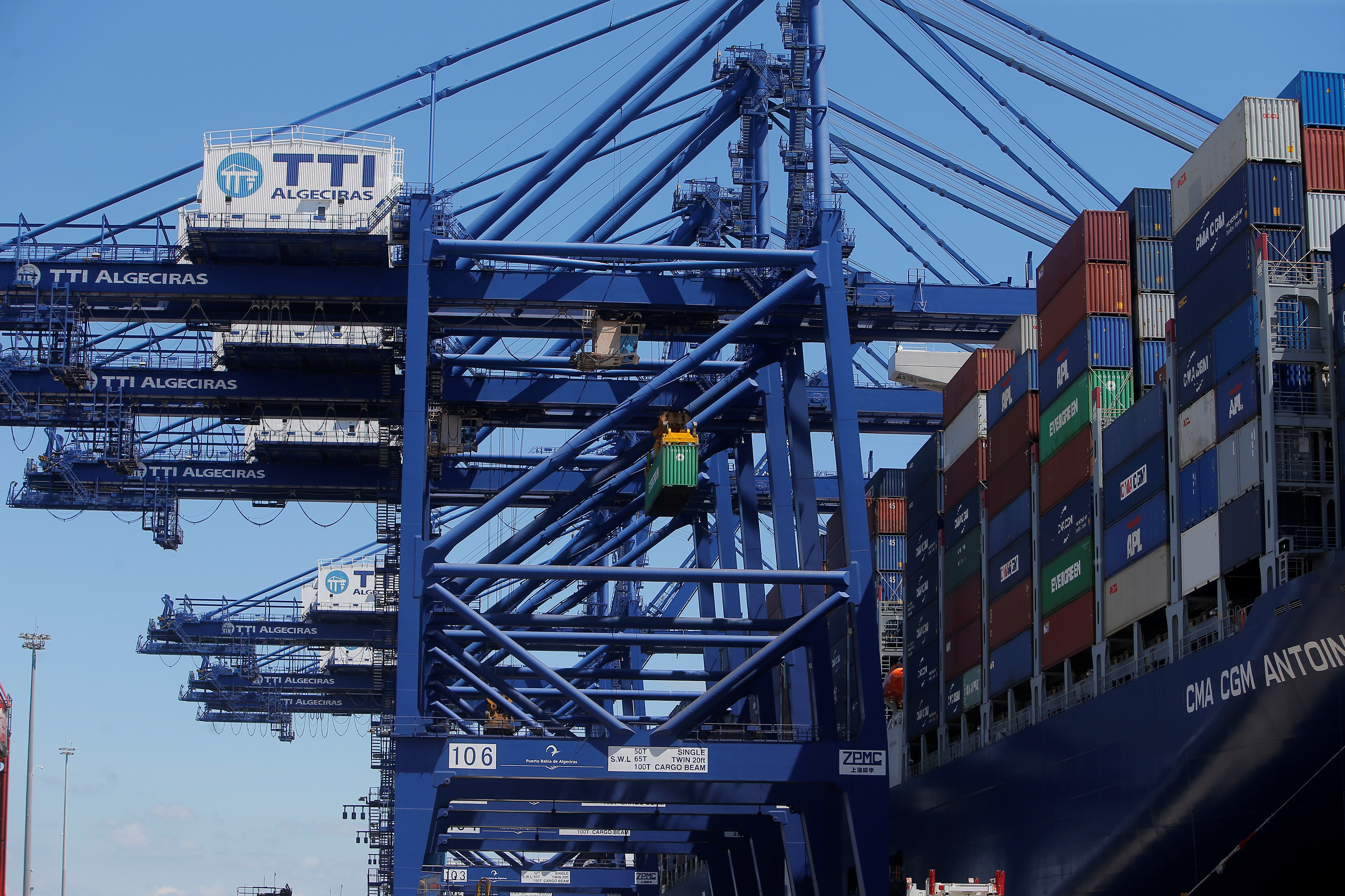 A crane loads a container on the mega cargo ship "Antoine de Saint Exupery" at the Total Terminal International Algeciras before leaving the port of Algeciras