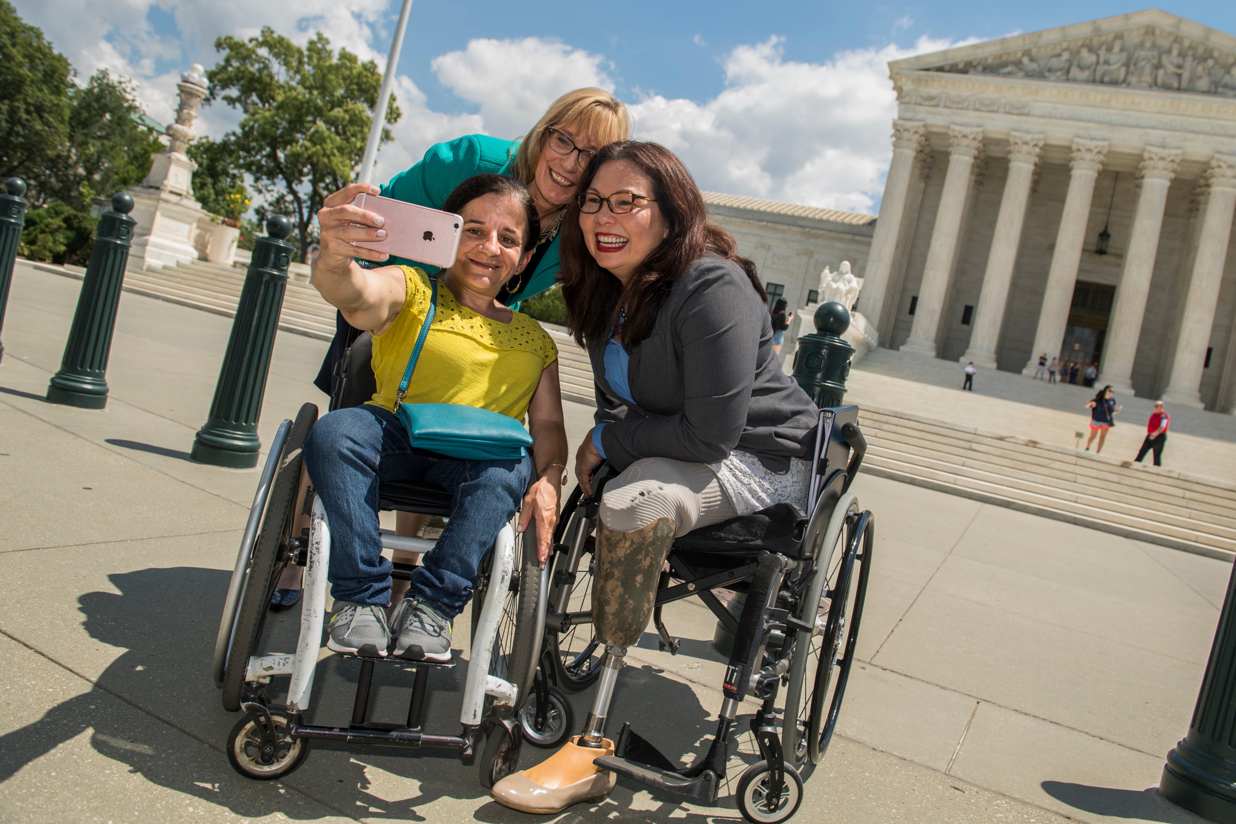 Sens. Tammy Duckworth, D-Ill., right, Maggie Hassan, D-N.H., and Colleen Flanagan of Disability Action for America, take a selfie after a news conference outside of the Supreme Court to mark the 27th anniversary of the Americans with Disability Act and oppose Medicaid cuts in the Republicans' healthcare plan on July 26, 2017. (Tom Williams&mdash;CQ-Roll Call, Inc. / Getty)
