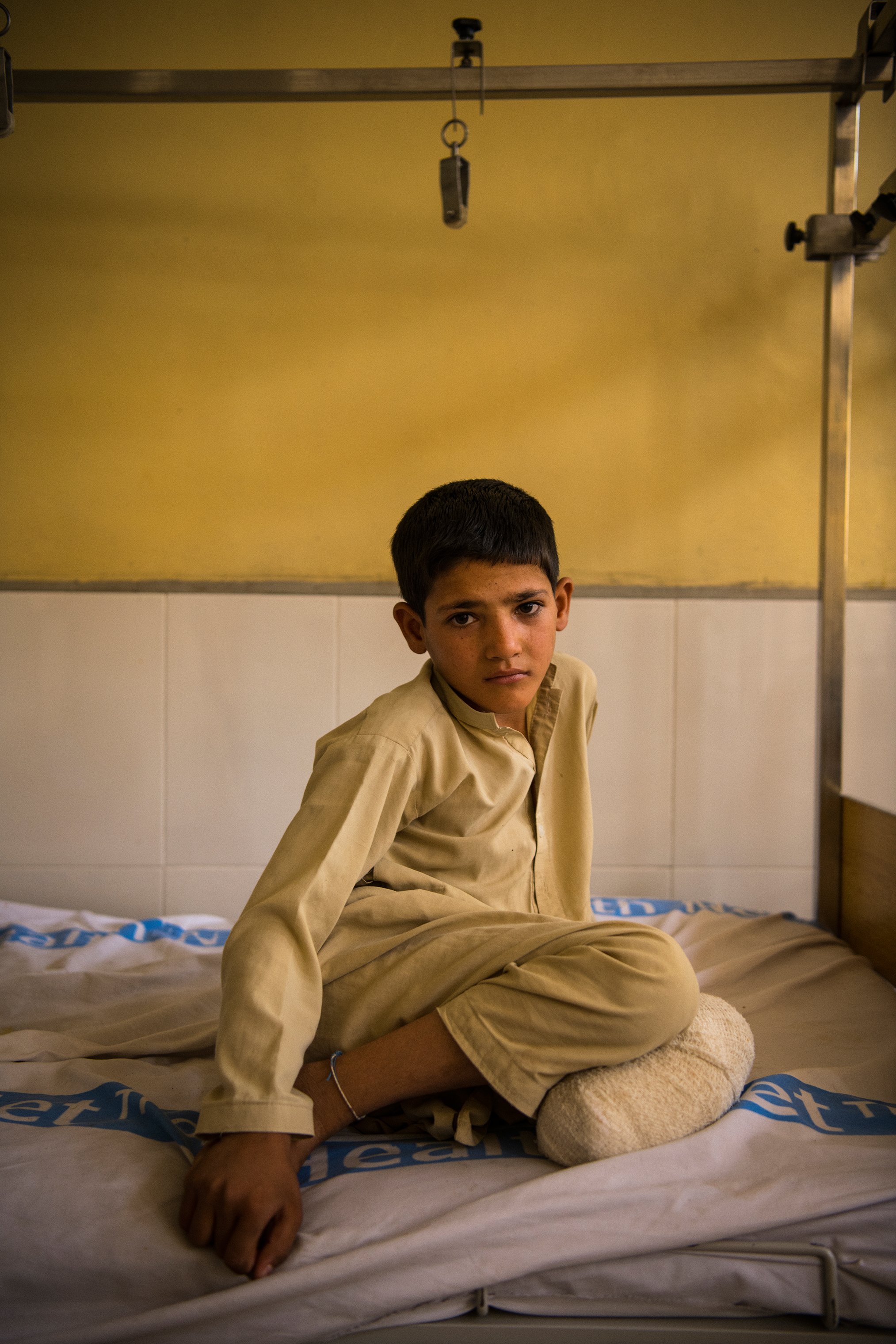 Bashir sits on a bed during a hospital visit by his extended family. (Andrew Quilty for TIME)