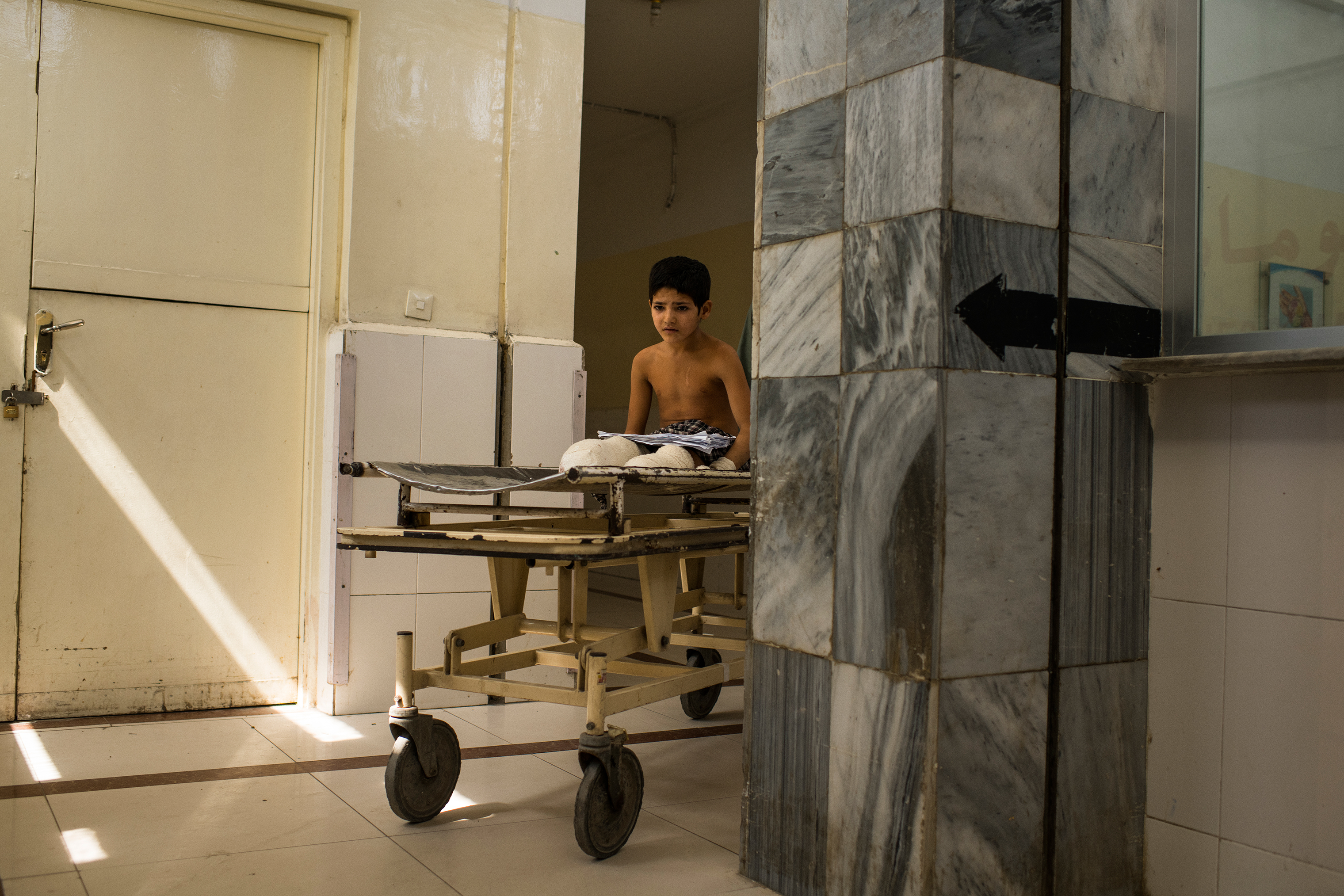 Abdul Rashid is pushed by his father, Hamisha Gul, on a gurney before a surgery. (Andrew Quilty for TIME)