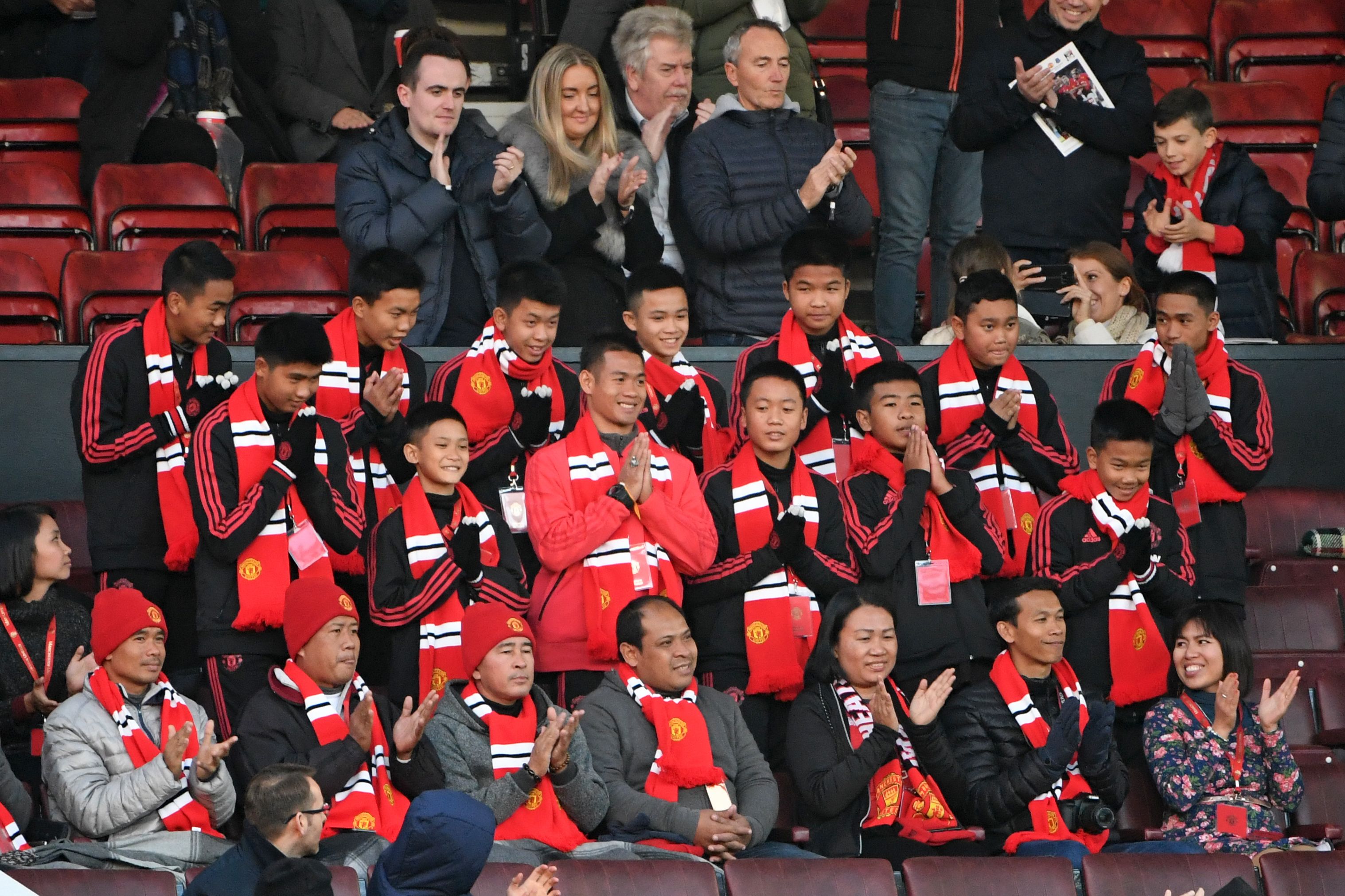 Thai coach Ekkapol Chantawong (center) and members of the "Wild Boars" football team take their seats in the stand for the English Premier League football match between Manchester United and Everton at Old Trafford in Manchester, England, on Oct. 28, 2018. (Paul Ellis—AFP/Getty Images)