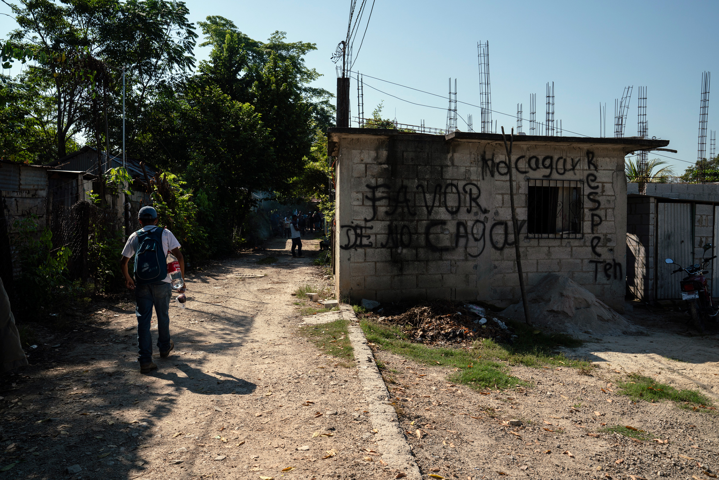 Migrants walk towards the train station near Palenque, Chiapas, on Oct. 26. The graffiti reads, “Please do not sh-t here. Be respectful.” (Veronica G. Cardenas for TIME)