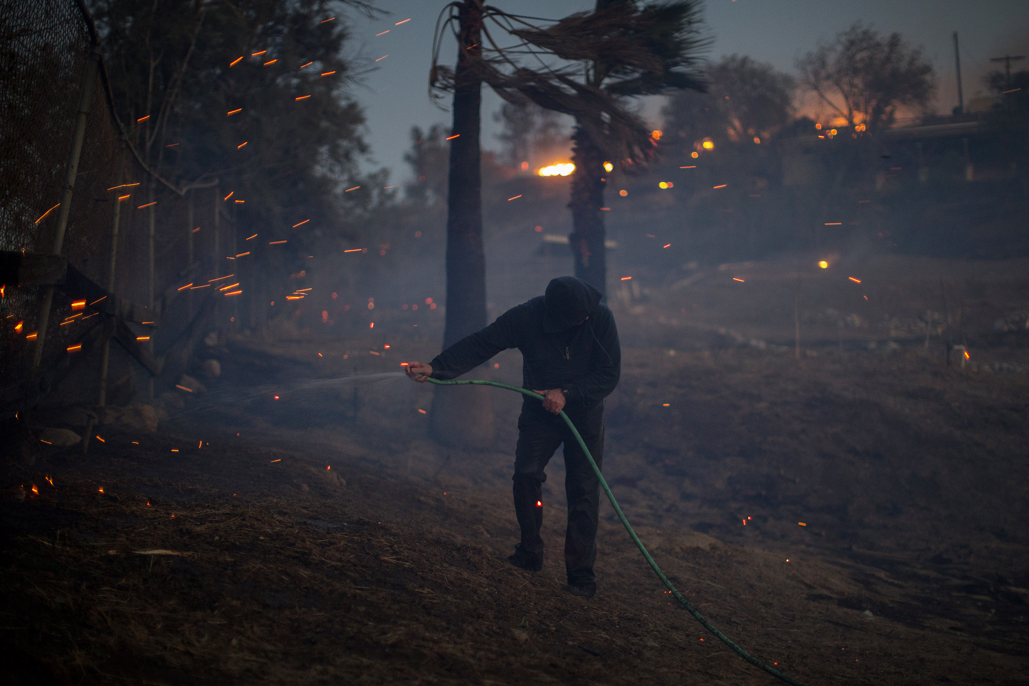 A strong wind blows embers around a resident hosing his burning property during the Creek Fire on December 5, 2017 in Sunland, California. (David McNew—Getty Images)