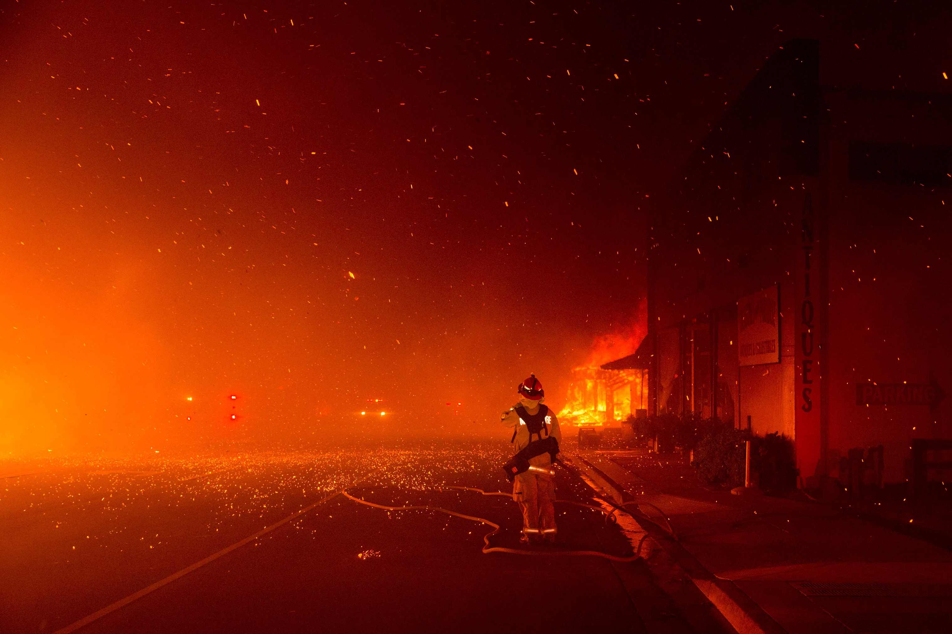 A fire fighter stands at the ready to protect a building across the street, as the Camp Fire burned out of control through Paradise, fueled by high winds in Butte County, Calif., on Nov. 8, 2018. (Peter Dasilva—EPA-EFE/Shutterstock)