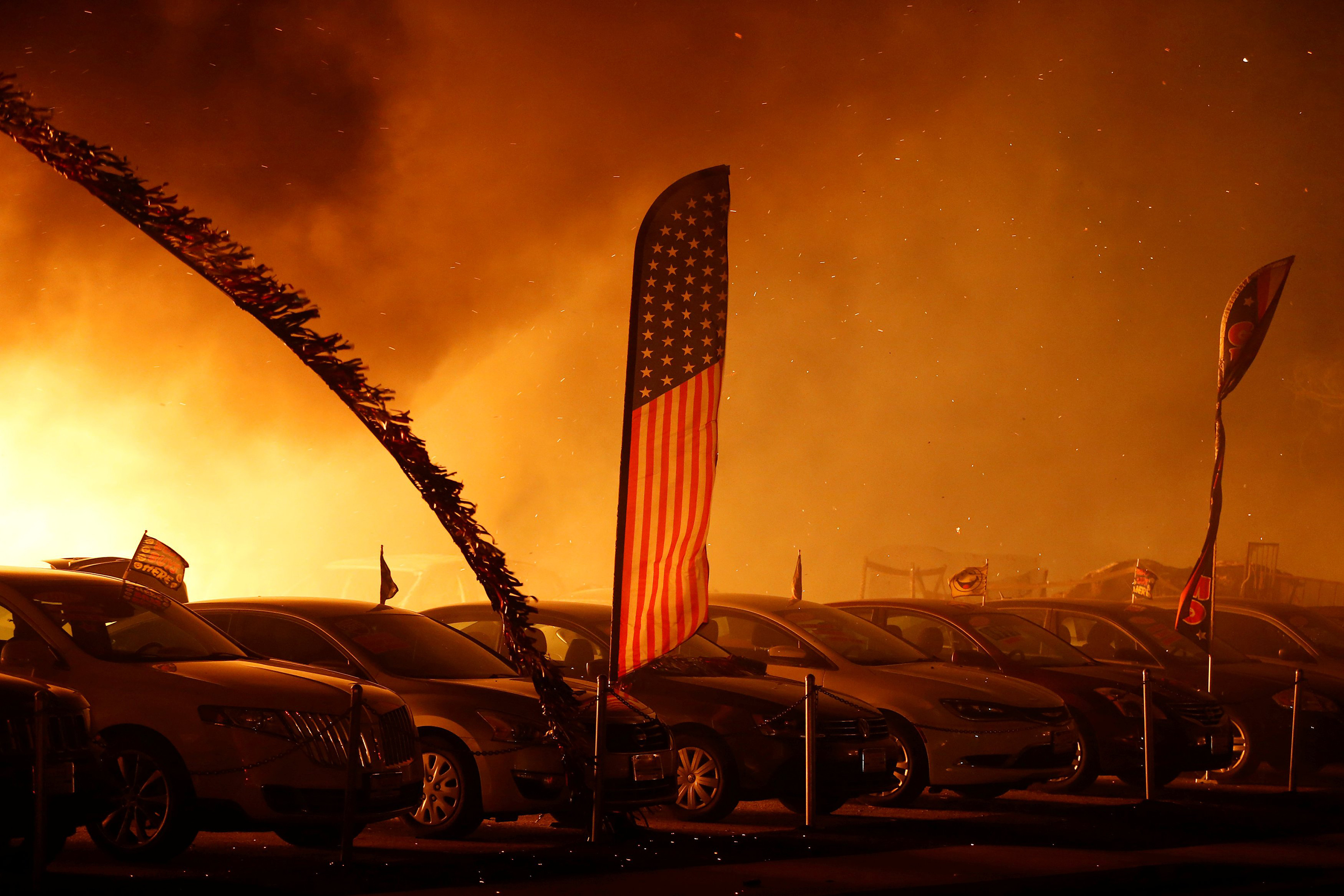 An American flag is seen at an engulfed car dealership during the Camp Fire in Paradise, Calif., on Nov. 8. (Stephen Lam—Reuters)
