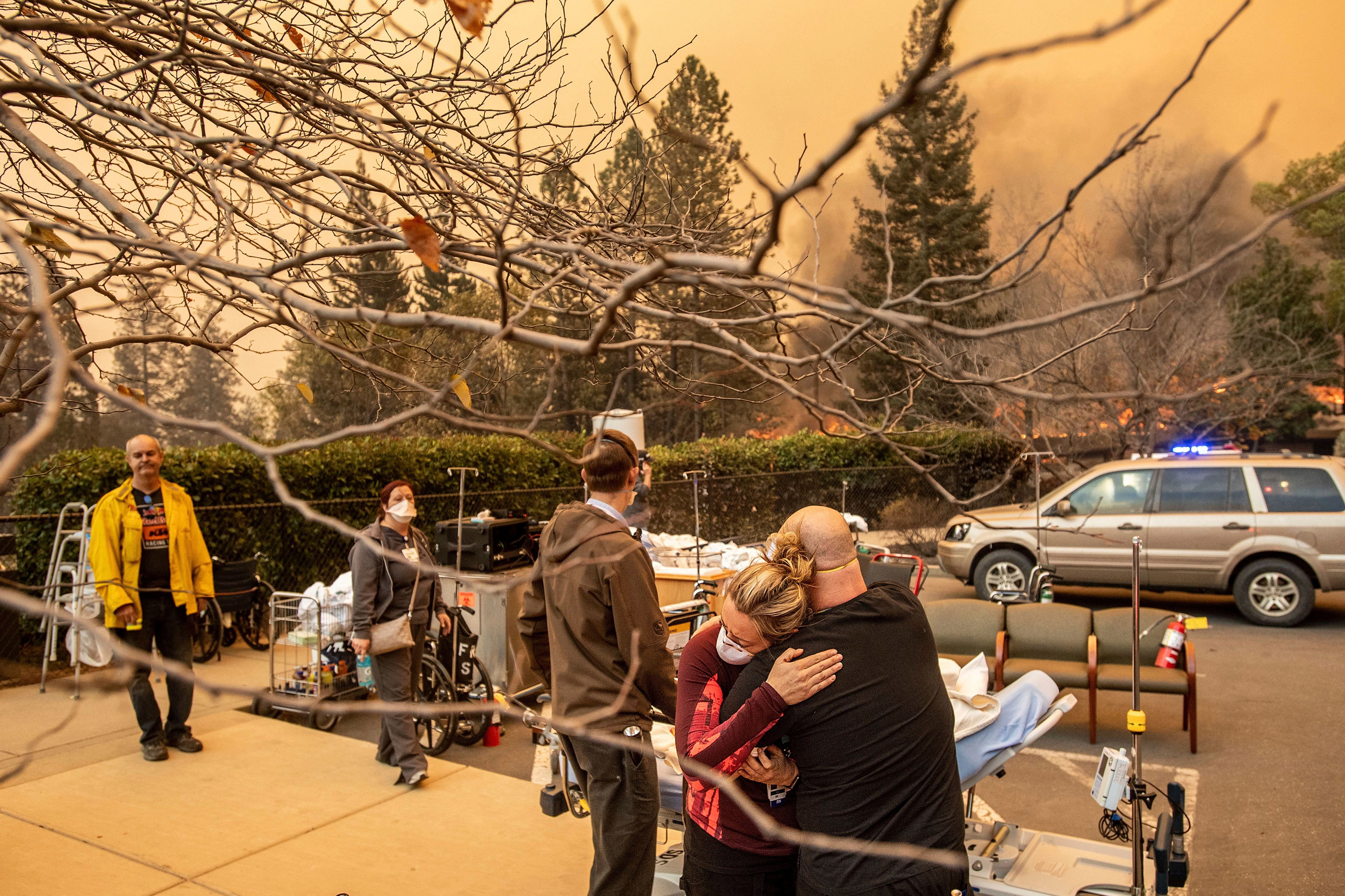 Nurse Cassie Lerossignol hugs a coworker as the Feather River Hospital burns while the Camp Fire rages through Paradise, Calif., on Nov. 8. (Noah Berger—AP/Shutterstock)