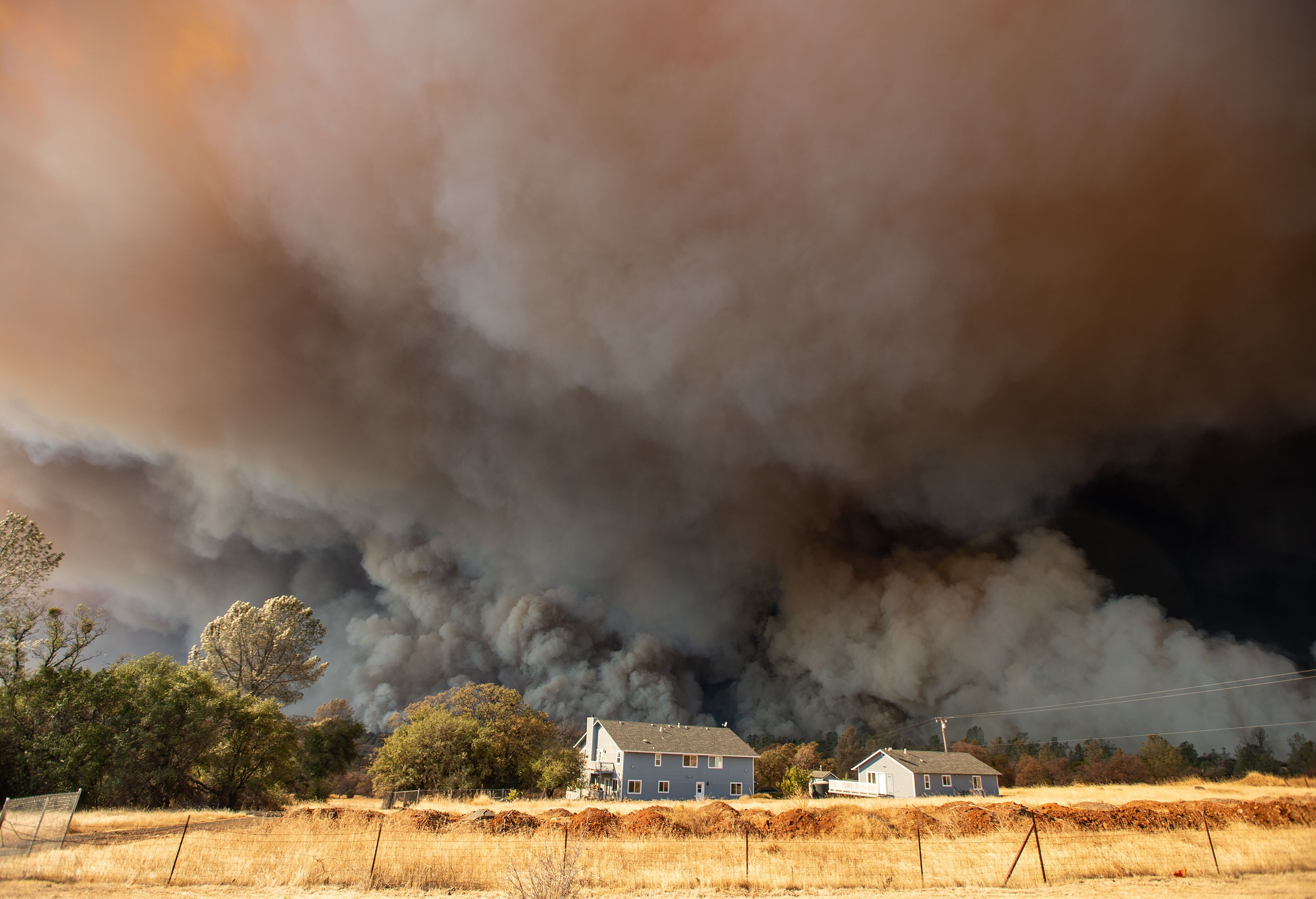 A home is overshadowed by towering smoke plumes as the Camp fire races through town in Paradise, Calif. on Nov. 8. (Josh Edelson—AFP/Getty Images)