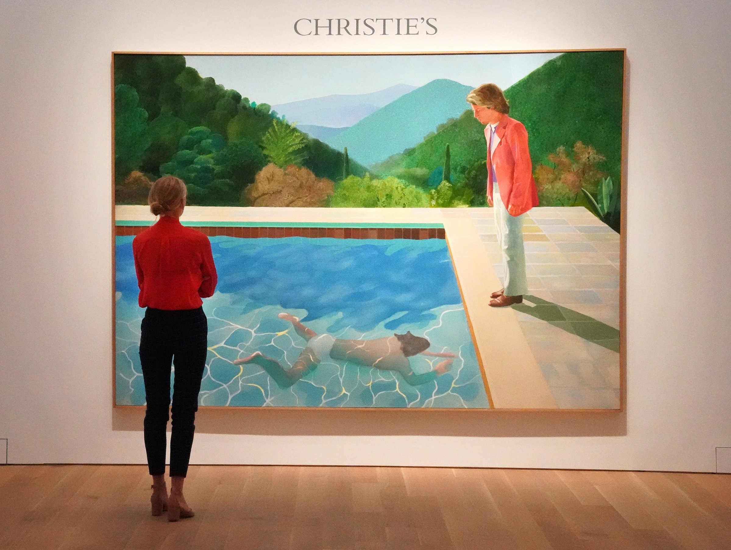 A woman looks at David Hockneys "Portrait of an Artist (Pool with Two Figures)" during a press preview on September 13, 2018 at Christie's New York. - The painting is to be auctioned during Christie's November 2018 Evening Sale of Post-War and Contemporary Art. Christie's expects the painting to sell for 80 million USD, making the work the most valuable piece of art by a living artist ever sold at auction.