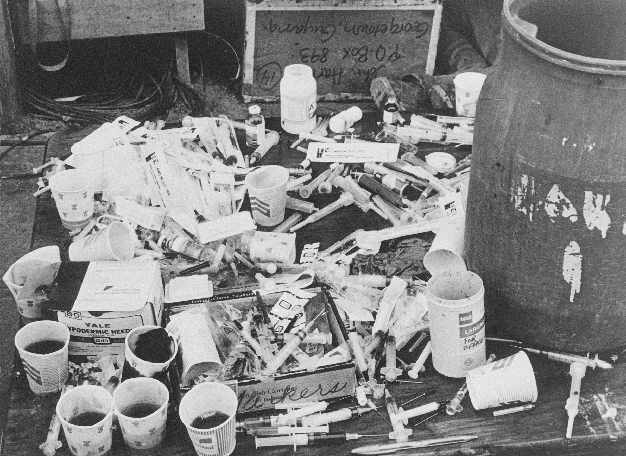 A pile of paper cups with cyanide-laced fruit punch, and a pile of hypodermic syringes, found at Jonestown by Guyanese officials. (Bettmann Archive)