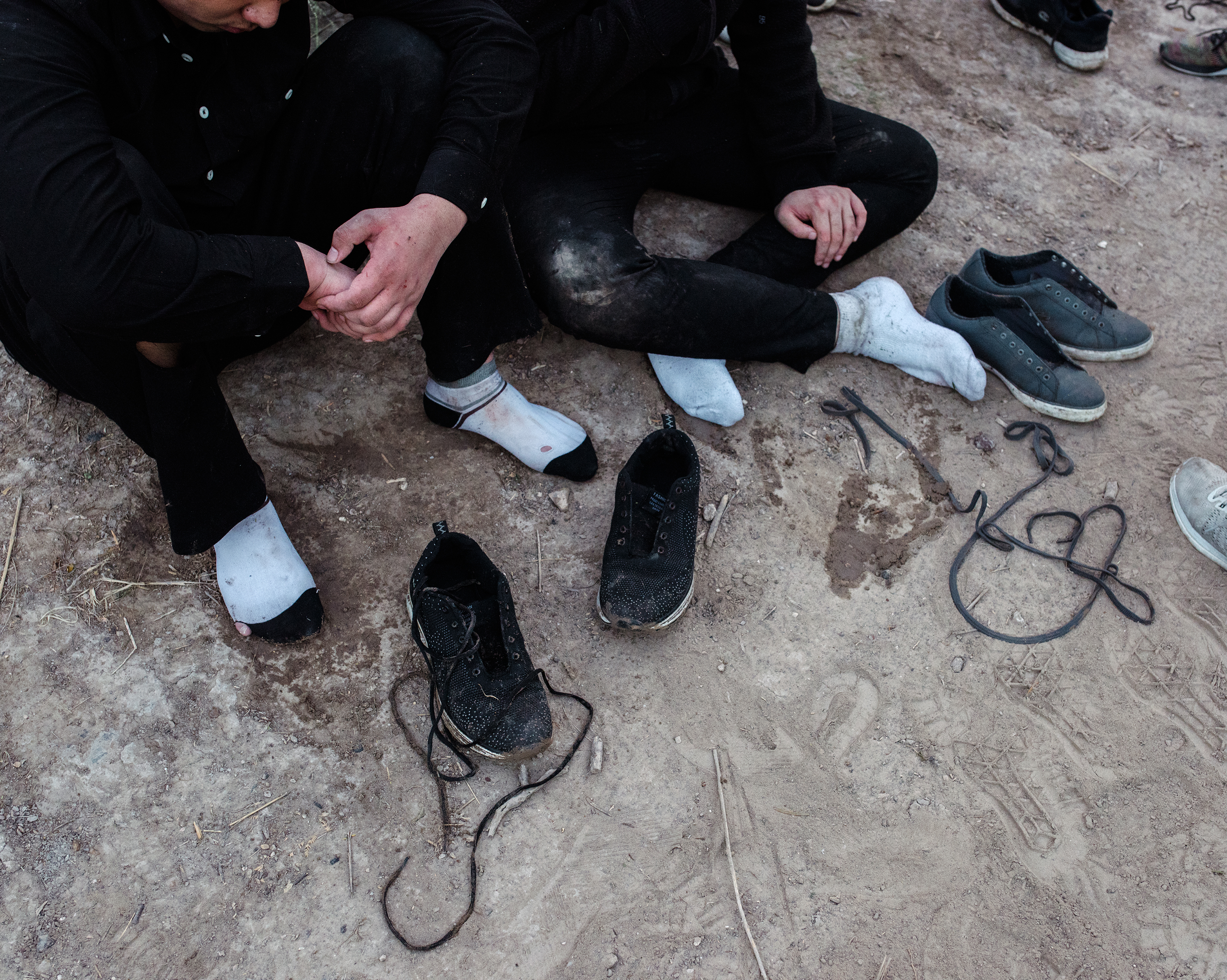 Members of a group of migrants from China and Guatemala unlace their shoes before being taken into custody, after illegally crossing the border through the Rio Grande, on Sept. 25. (John Francis Peters for TIME)