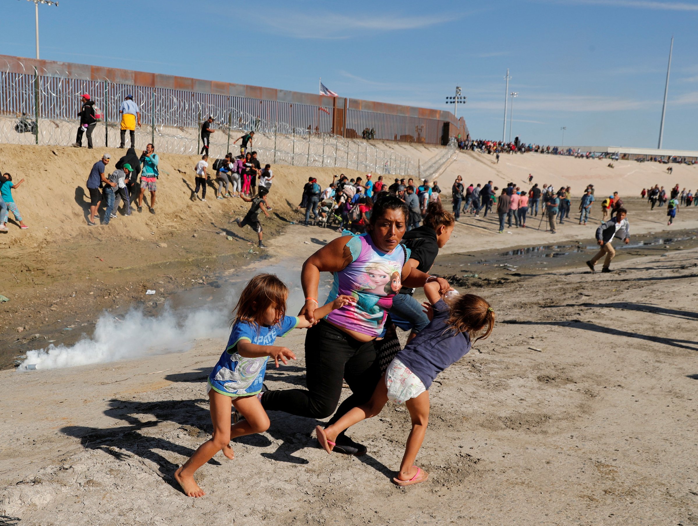 A migrant family, part of a caravan of thousands traveling from Central America to the United States, run away from tear gas
