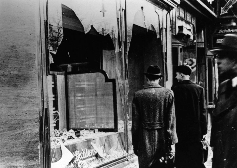 Nov. 10, 1938:  Three onlookers at a smashed Jewish shop window in Berlin following riots of the night of 9th November.