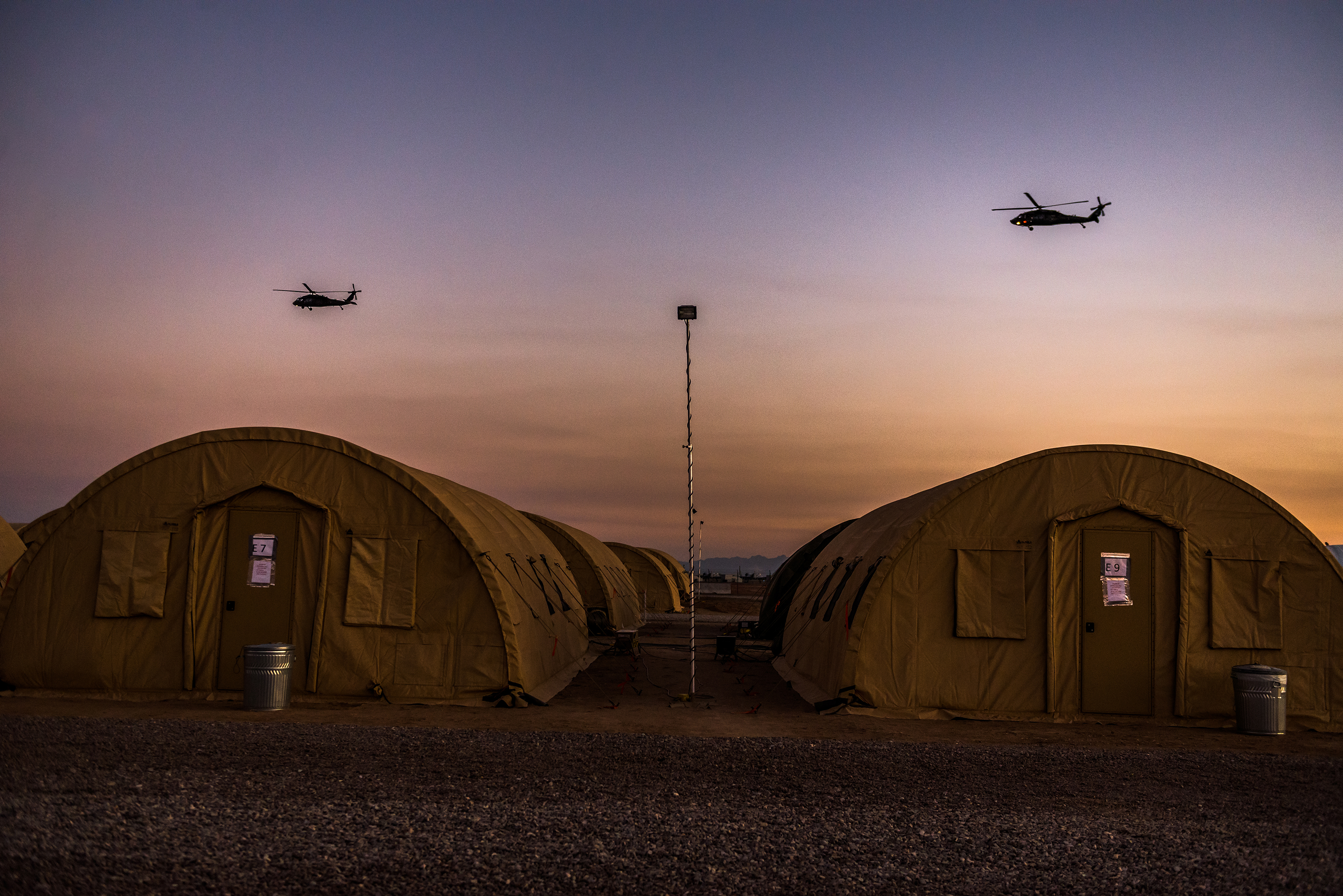 Helicopters fly over rapidly assembled tents used for army sleeping quarters. (Meridith Kohut for TIME)