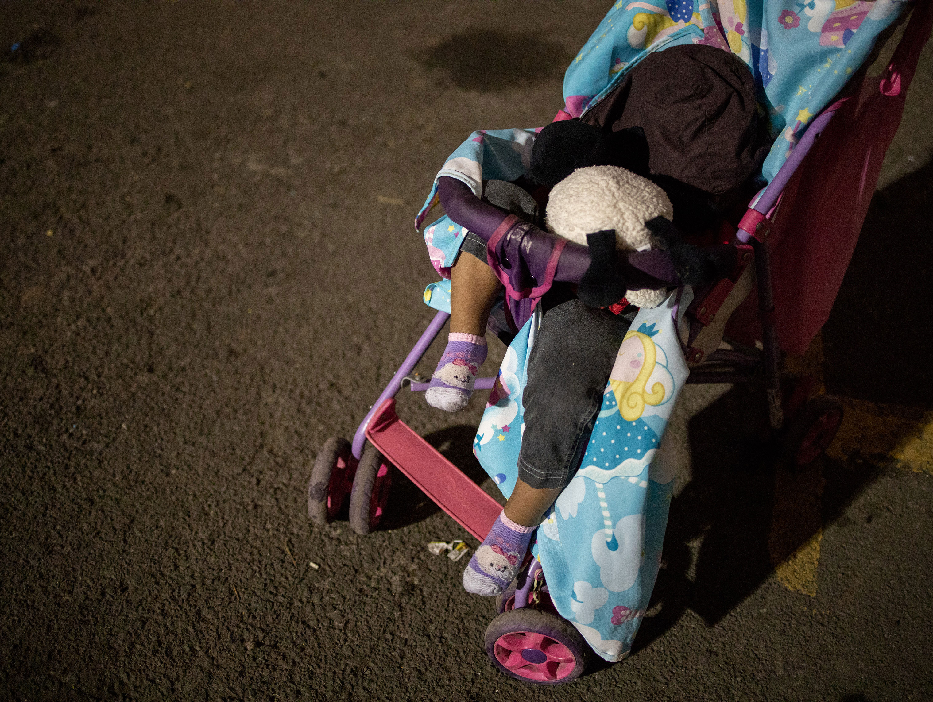 A baby who has just arrived the Jesus Martinez stadium, in Mexico City sleeps as his parents sort through donated clothes nearby, on Nov. 4, 2018. (Jerome Sessini—Magnum Photos for TIME)