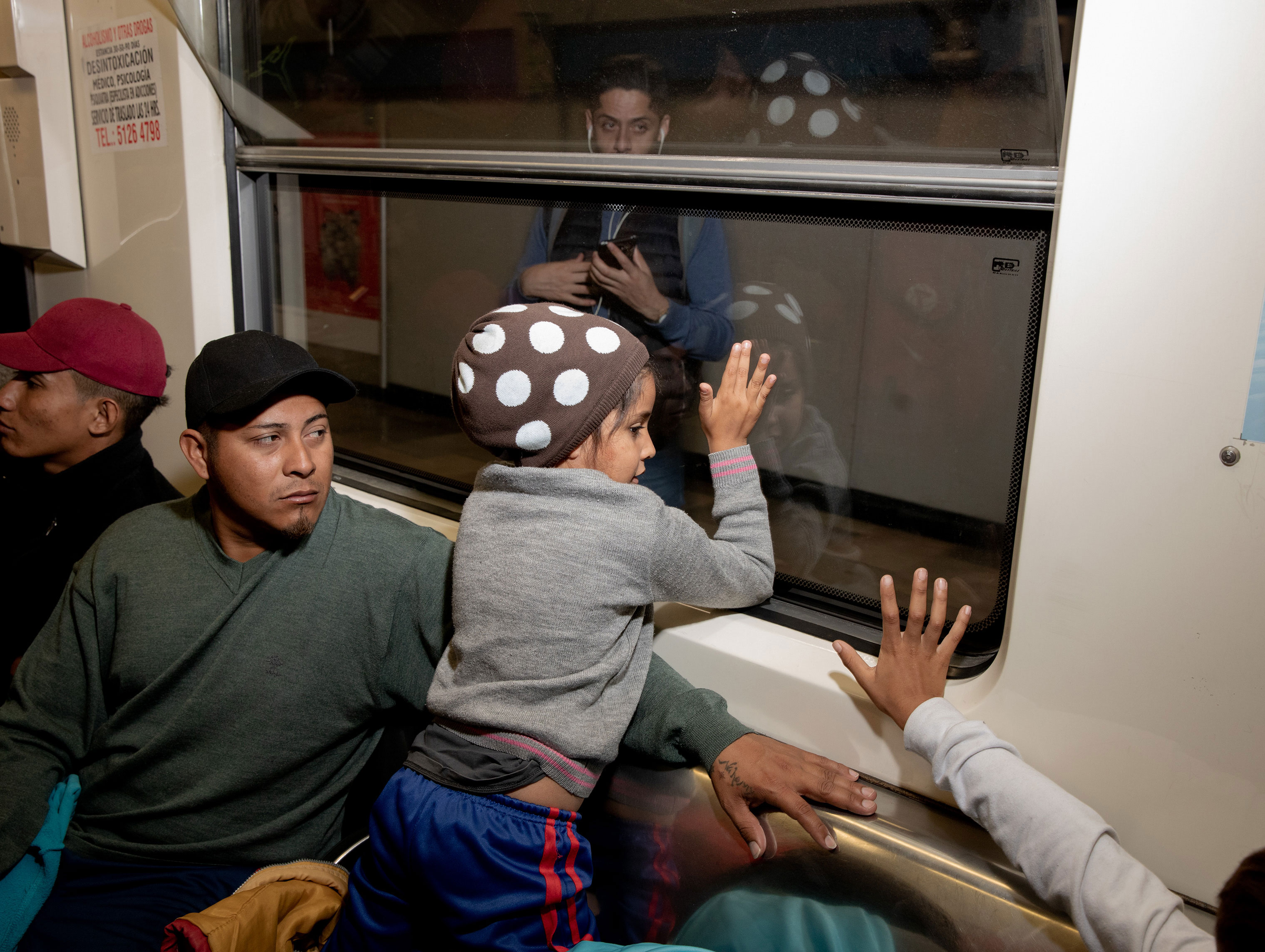 The migrant caravan exited Mexico City on the metro on the morning of Nov. 10, 2018. A young girl waves to a woman on the other side of the metro car. (Jerome Sessini—Magnum Photos for TIME)