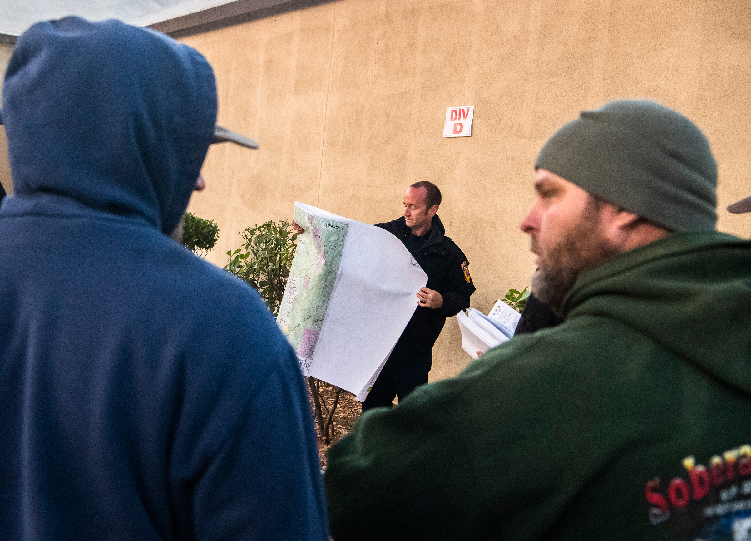 A firefighter unfurls a map for the division Delta briefing at the Camp Fire incident command post on Nov. 20, 2018. (Stuart Palley for TIME)