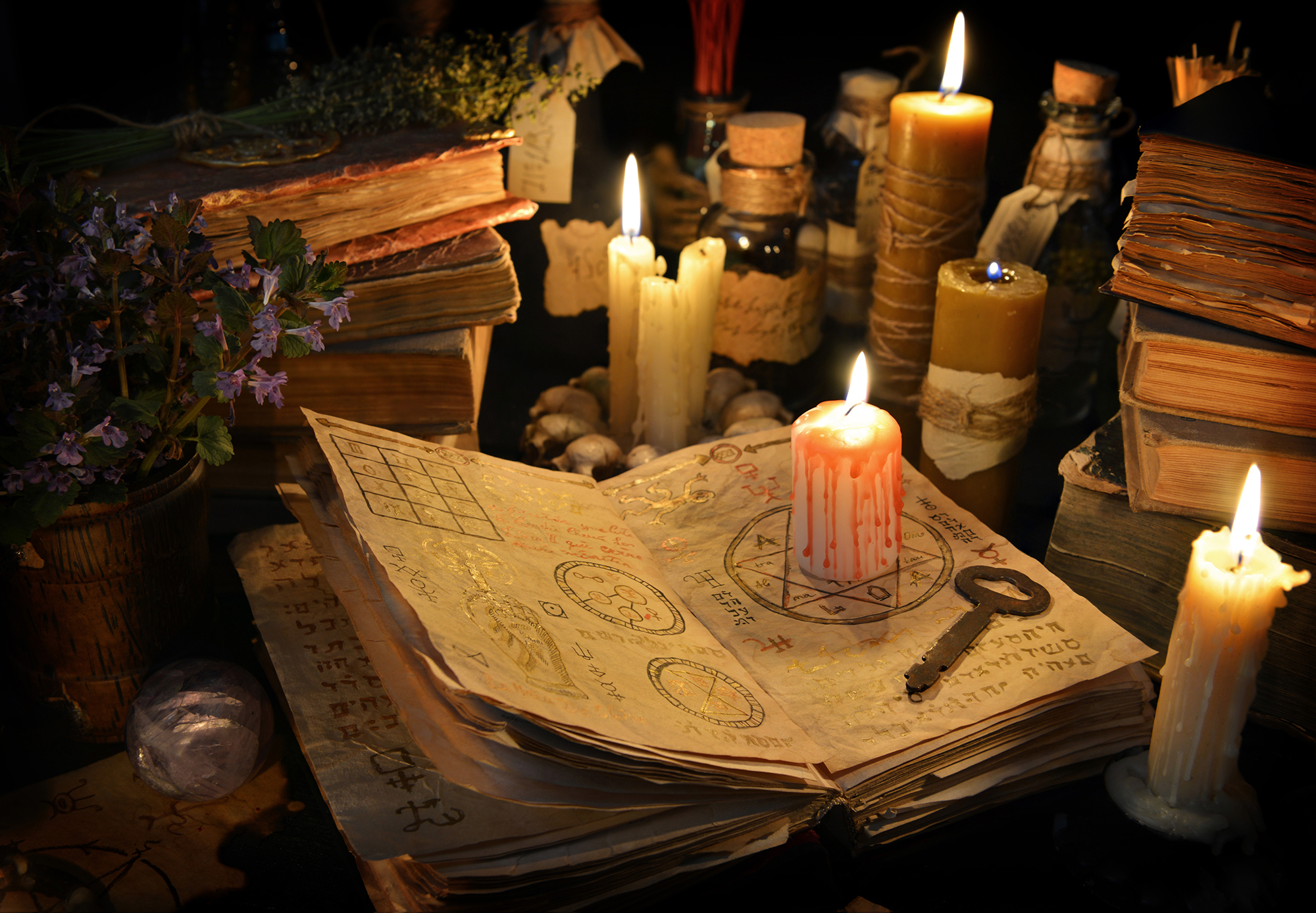 Bloody candle with rustic key on witch book in candle light