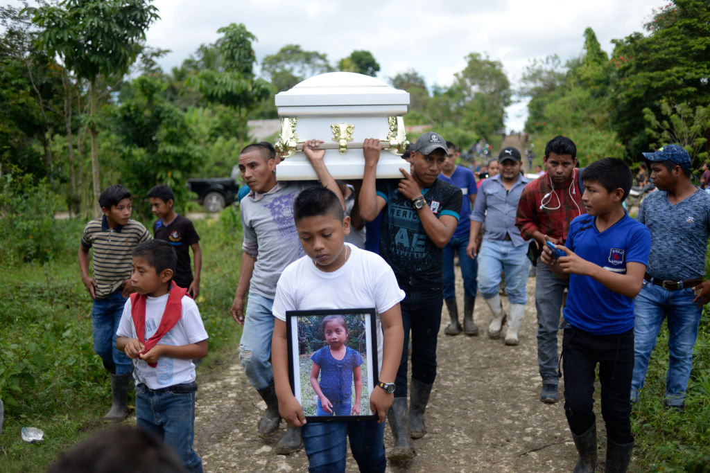 A boy carries a picture of Guatemalan seven-year-old Jakelin Caal, who died in a Texas hospital two days after being taken into custody by US border patrol agents in a remote stretch of the New Mexico desert. (JOHAN ORDONEZ—AFP/Getty Images)