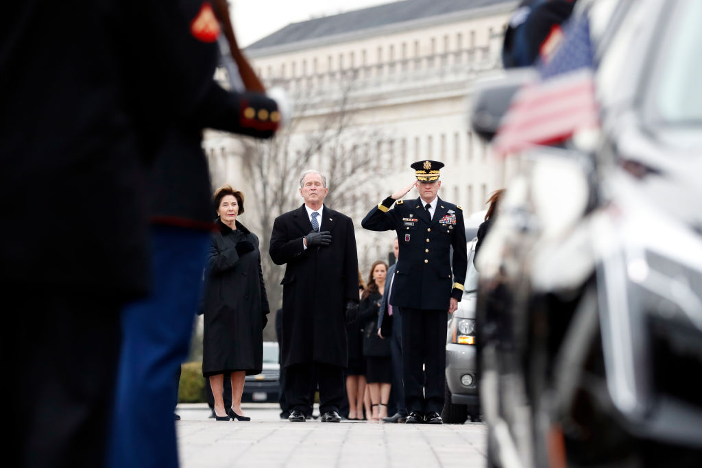 Former President George W. Bush and former first lady Laura Bush watch as Former President George H. W. Bush's casket leaves the U.S. Capitol