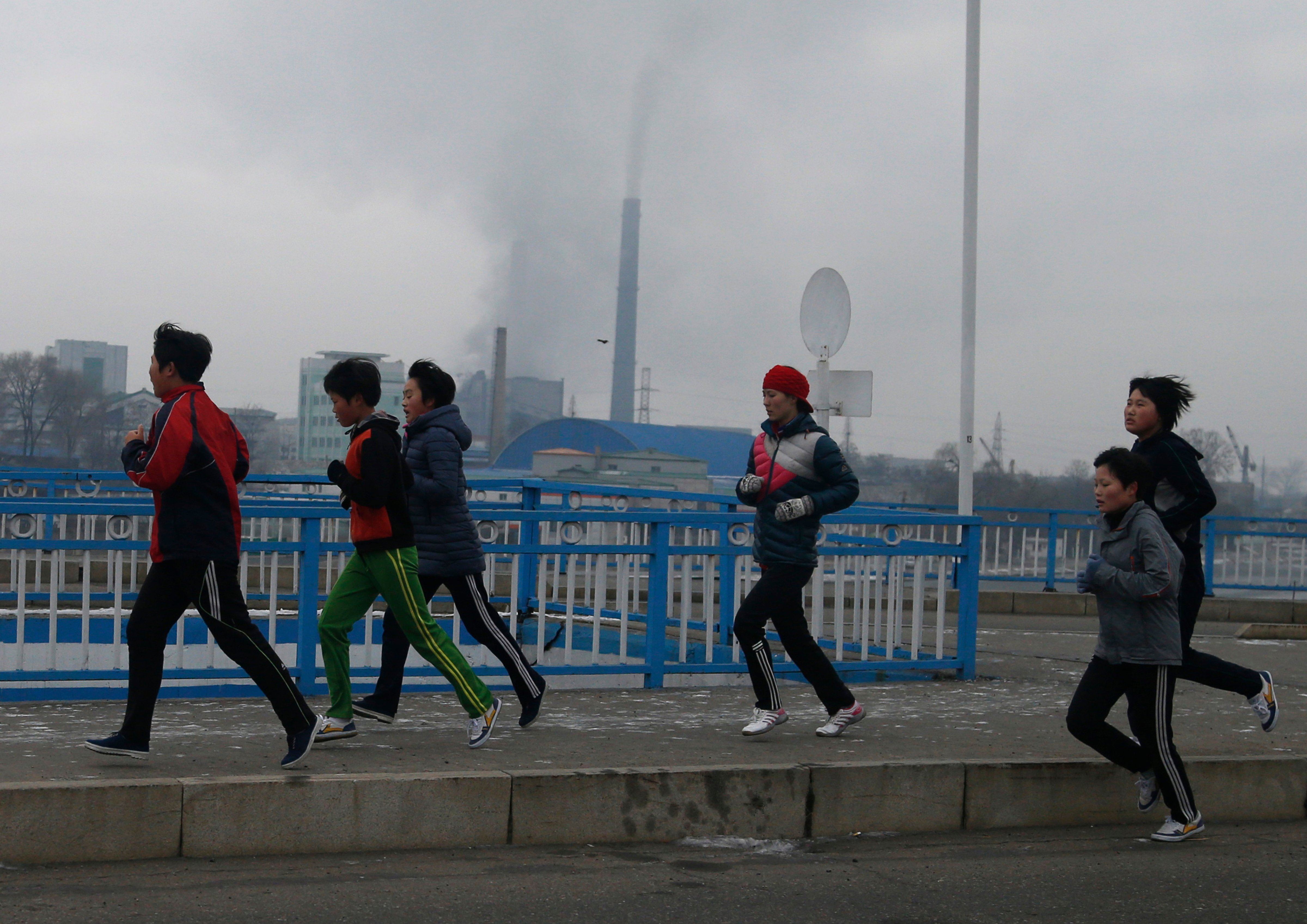 North Korean youths take their morning run as smoke billows from the chimneys of Pyongyang Power Plant in the background in Pyongyang, North Korea, on Dec. 15, 2018. (Dita Alangkara—AP/REX/Shutterstock)