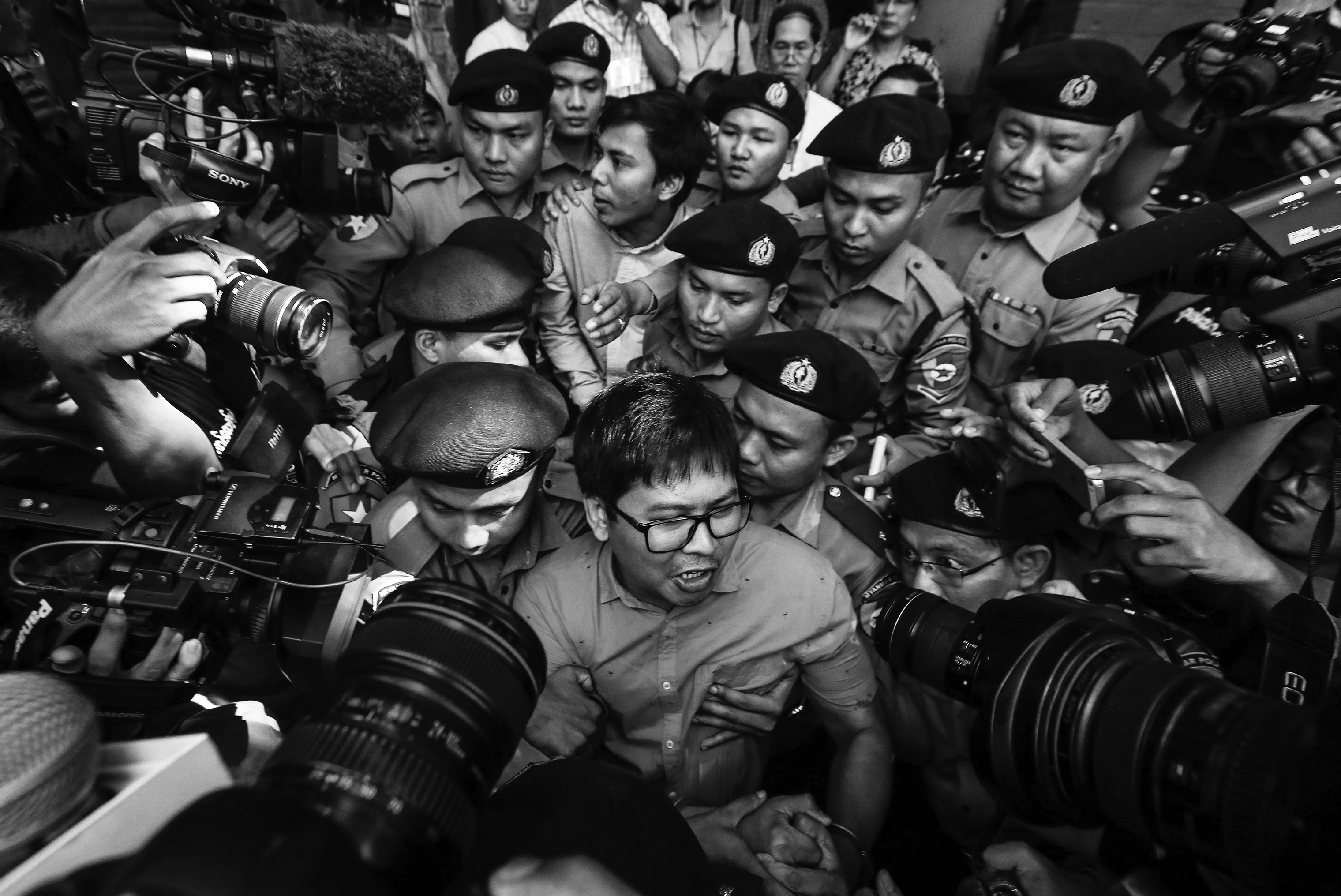Reuters' journalists Wa Lone (C, front) and Kyaw Soe Oo (C, back) are escorted by police as they leave the court after their first trial in Yangon, Myanmar, 10 January 2018. Reuters journalists Wa Lone and Kyaw Soe Oo were arrested on the outskirts of Yangon city on 12 December 2017 by Myanmar police for allegedly possessing classified police documents. In September the journalists were convicted to seven years in prison. (Lynn Bo Bo—EPA-EFE/Shutterstock)