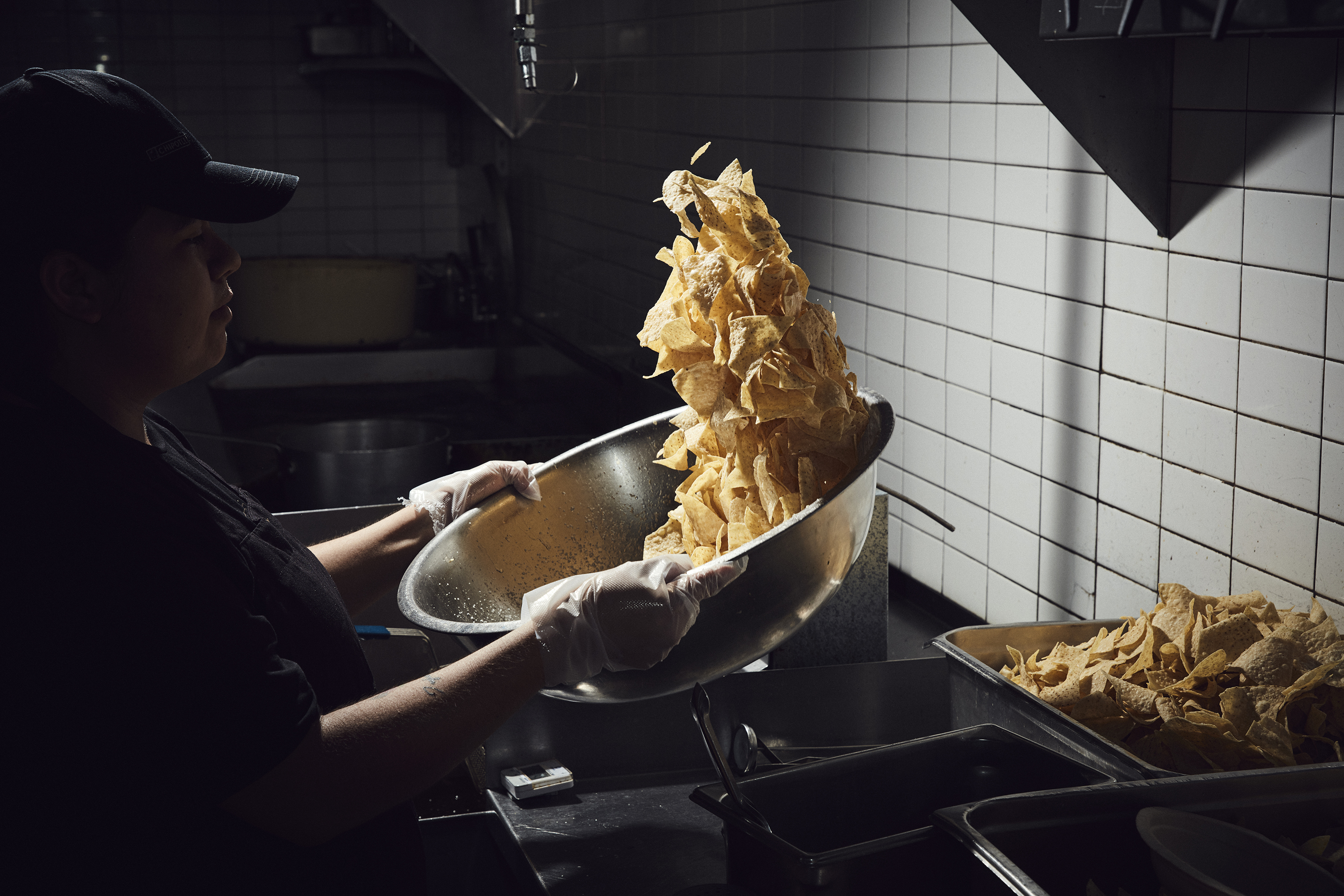 A Chipotle employee seasons chips at a location in Newport Beach, Calif. The company, founded in 1993, now has roughly 70,000 employees and 2,450 locations. (Shaughn and John for TIME)