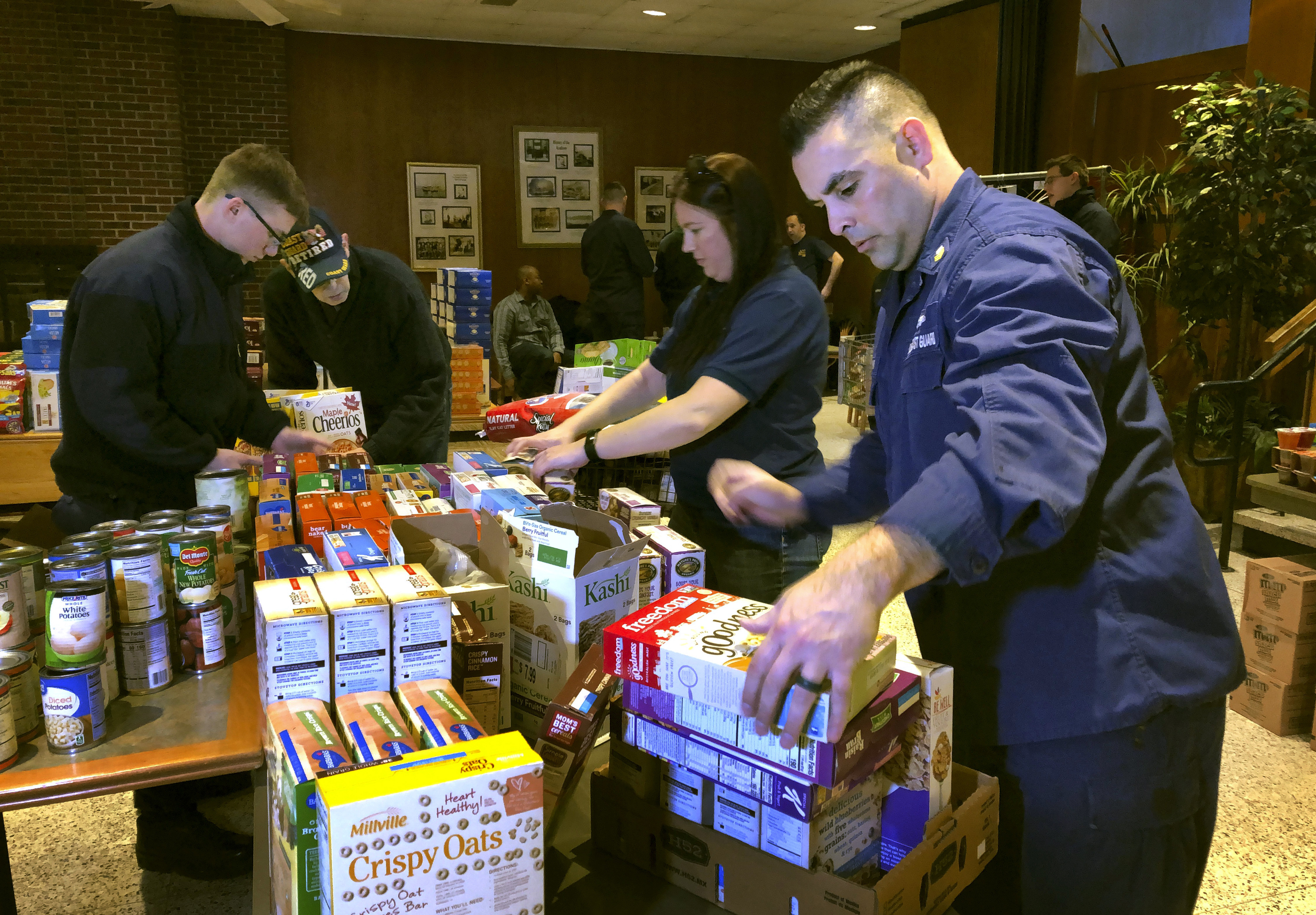 U.S. Coast Guard Culinary Specialist Jerry Wright, right, and Petty Officer 2nd Class Lauren Laughlin, second from right, stack boxes of donated cereal at a pop-up food pantry created at the Coast Guard Academy in New London, Conn., on Jan. 17, 2019. (Susan Haigh&mdash;AP)