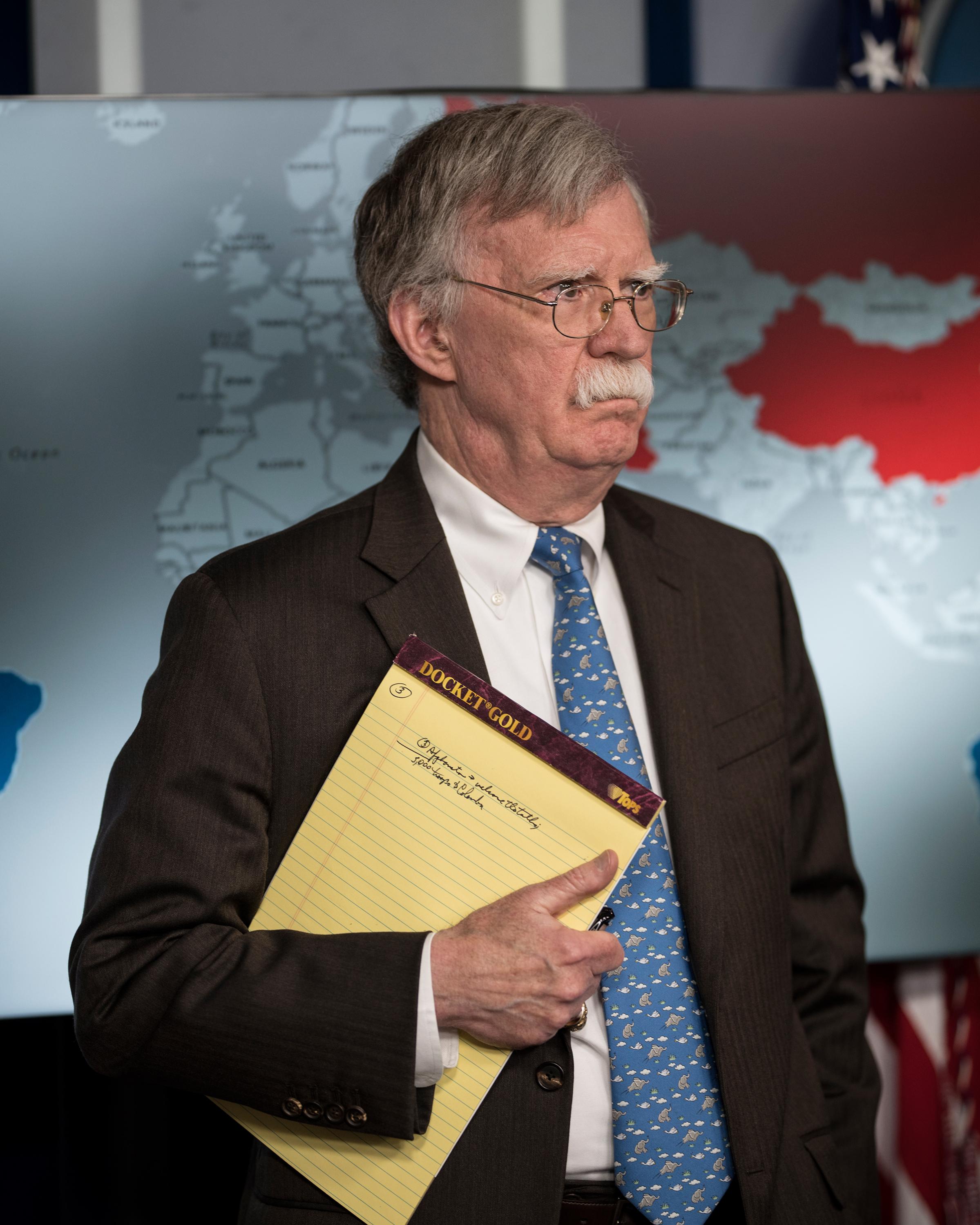 John Bolton holds a yellow legal pad reading "5,000 troops to Colombia."