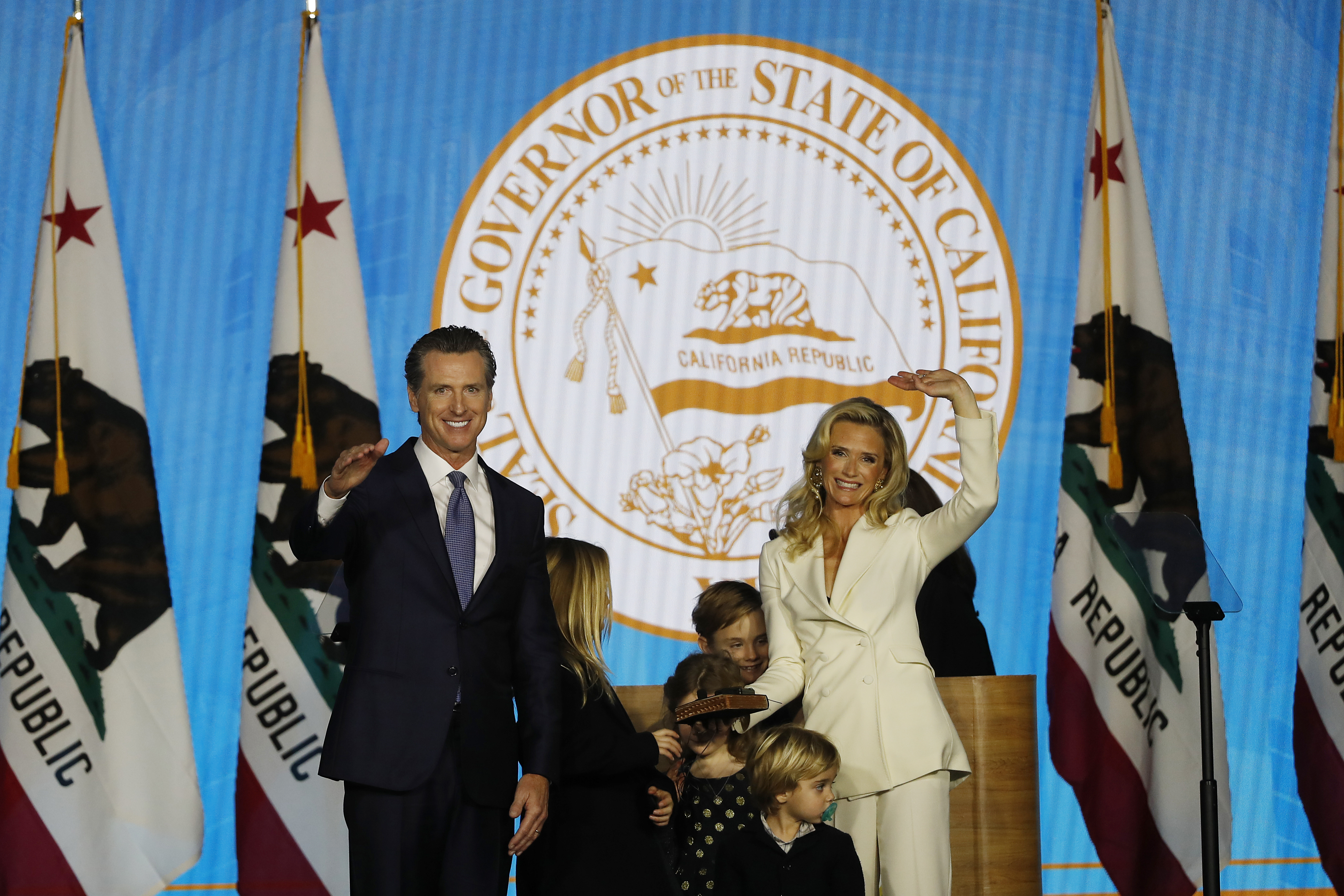 Governor Gavin Newsom and wife Jennifer Siebel Newsom gesture to the crowd after taking his oath of office on Jan. 7, 2019 in Sacramento, Calif. (Stephen Lam—Getty Images)