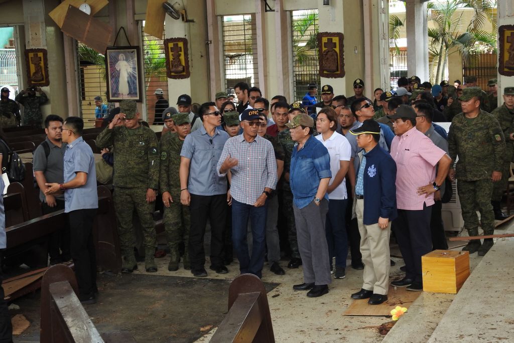 Philippine President Rodrigo Duterte (C, in blue shirt) accompanied by Defense Secretary Delfin Lorenzana (L, with spectacles) inspect the damaged area of a catholic cathedral in Jolo, Sulu province on Jan. 28, 2019. (Nickee Butlangan—AFP/Getty Images)