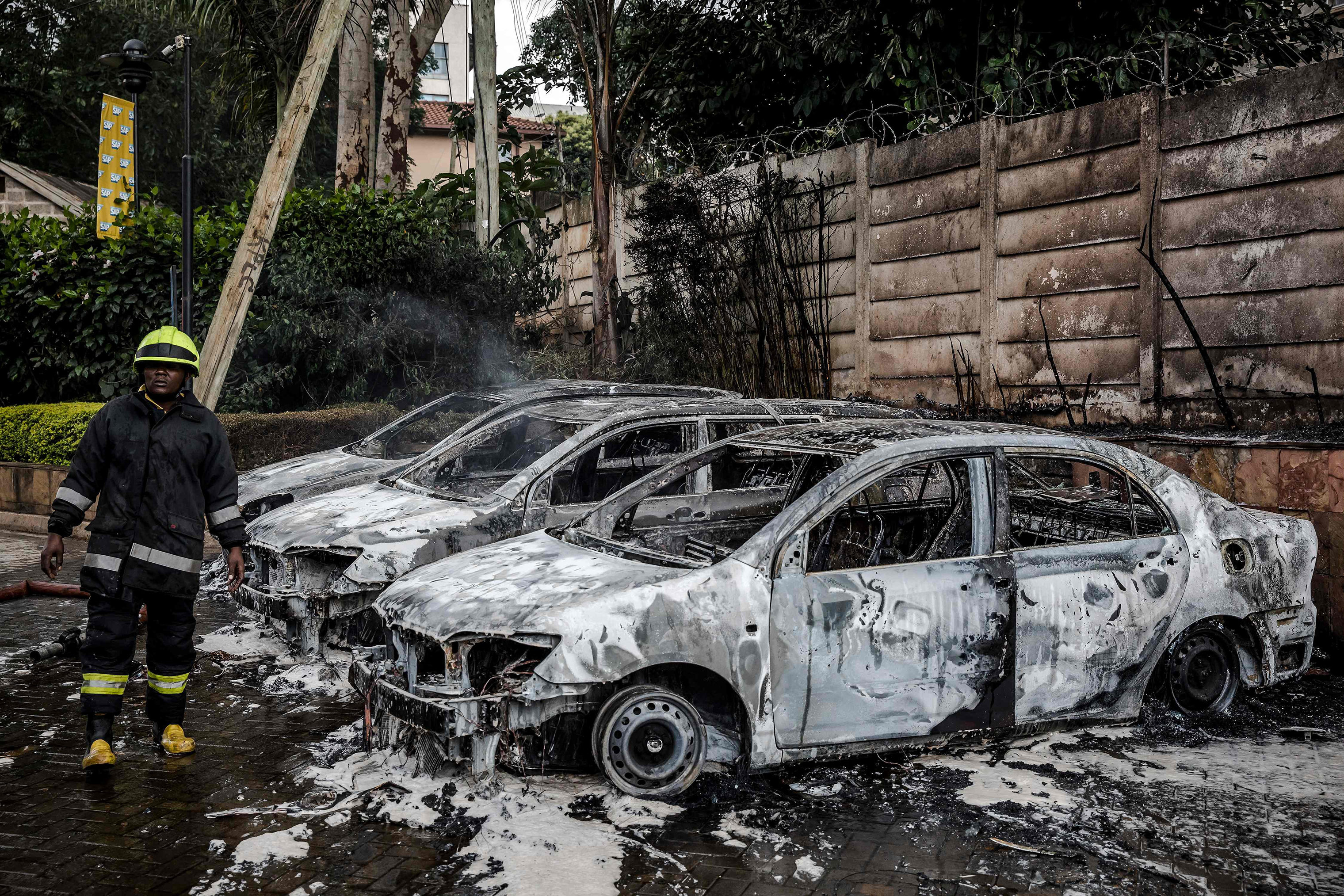 A firefighter stands next to the wreckage of cars in Nairobi's Westlands area. (Luis Tato—AFP/Getty Images)