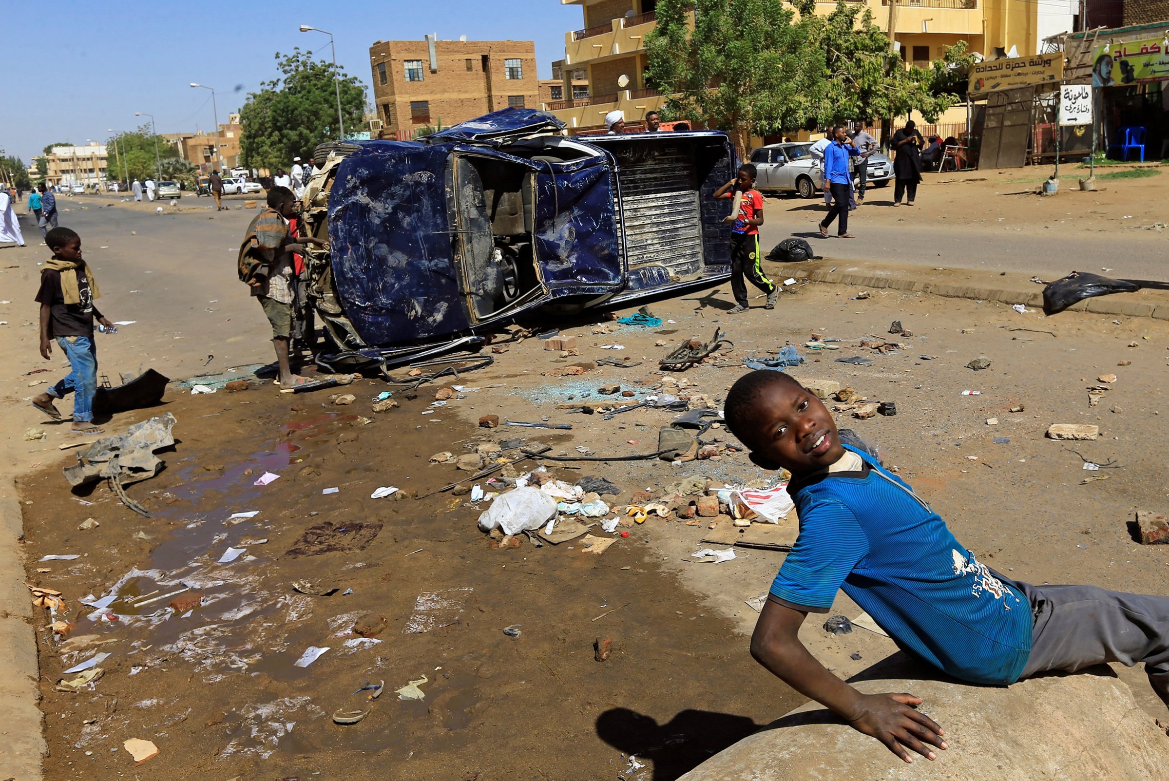 Children play near a police car flipped over and damaged by mourners near the home of a demonstrator who died of a gunshot wound sustained during anti-government protests in Khartoum, Sudan January 18, 2019.