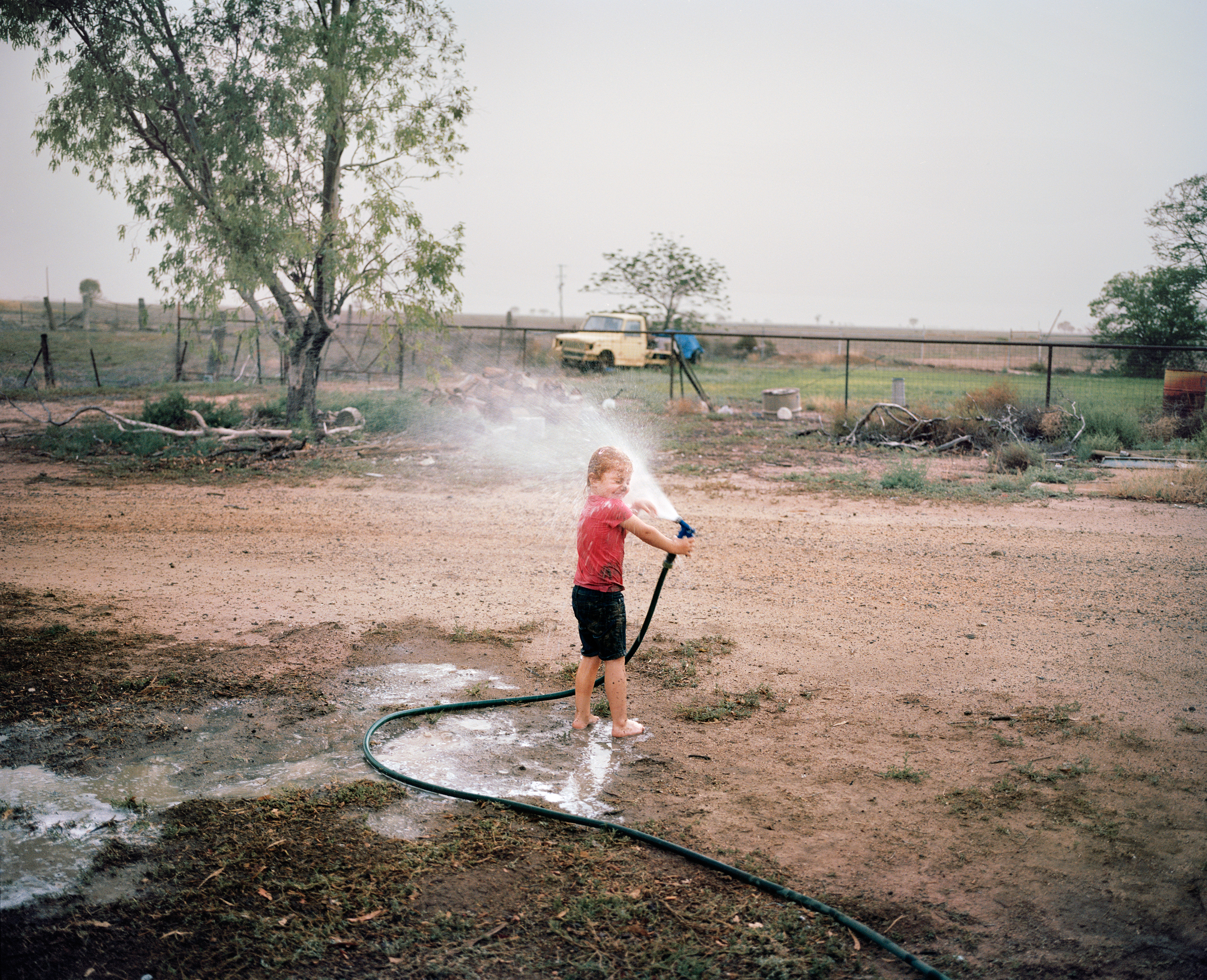 The daughter of farmer Ben Hawk plays with a hose at a Come by Chance store in New South Wales in December. Hawk did not plant crops last year because of the drought. While believing it's up to farmers to run a diverse business that is resilient enough to drought, Hawk says "it will be time to make some tough decisions if it doesn't rain in 2019." (Adam Ferguson for TIME)