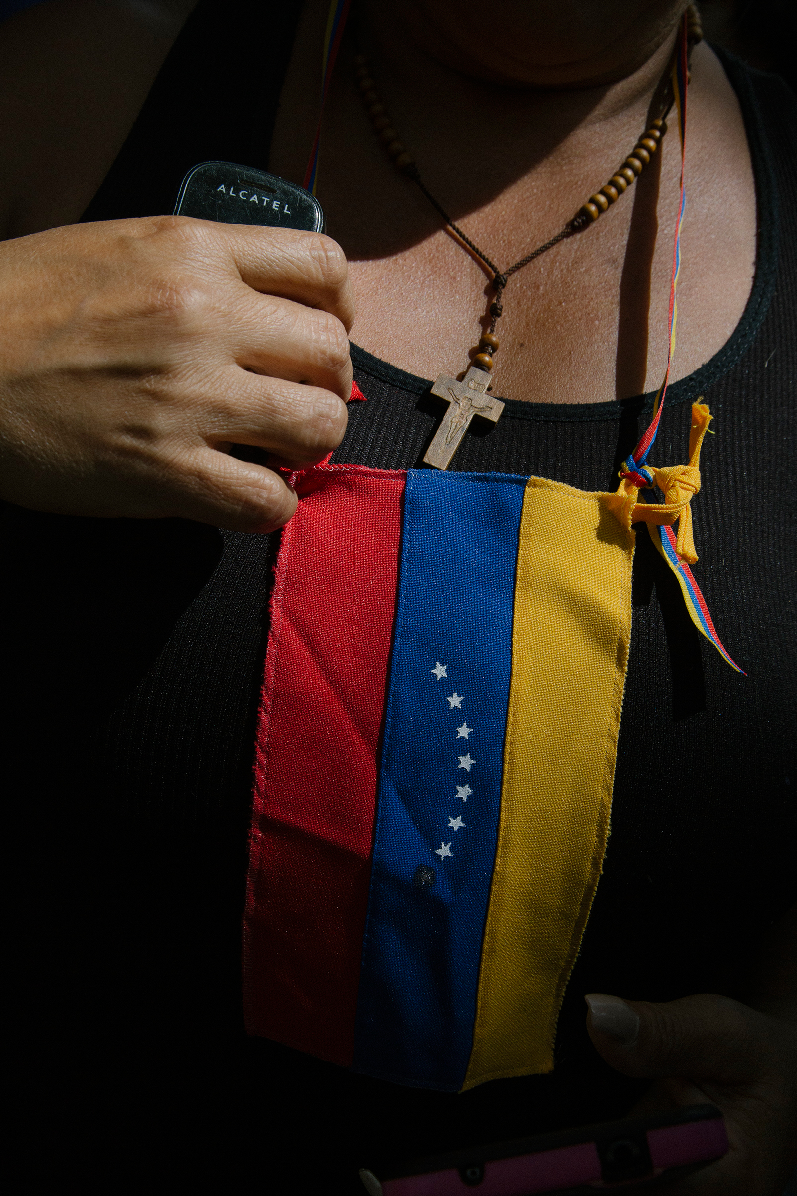 A woman fixes a flag on her chest during a news conference by Guaidó at the Bolivar Square of Chacao in Caracas on Jan. 25, 2019. (Andrea Hernandez)