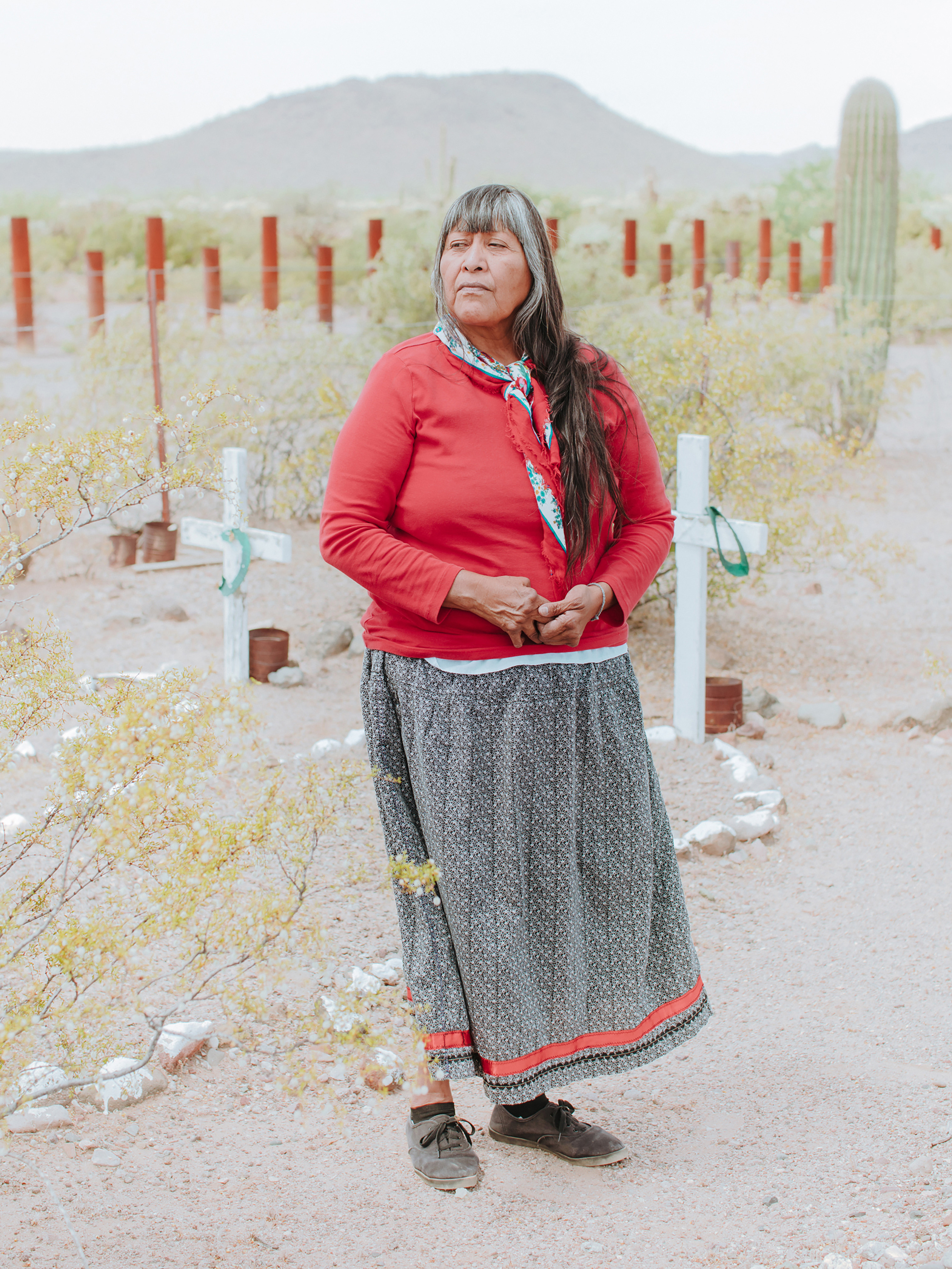 Ofelia Rivas poses in front of crosses her father made, marking the graves of two migrants who died from dehydration years before she was born in Tohono O'odham Nation, Ali Jek, Ariz. (Elliot Ross)