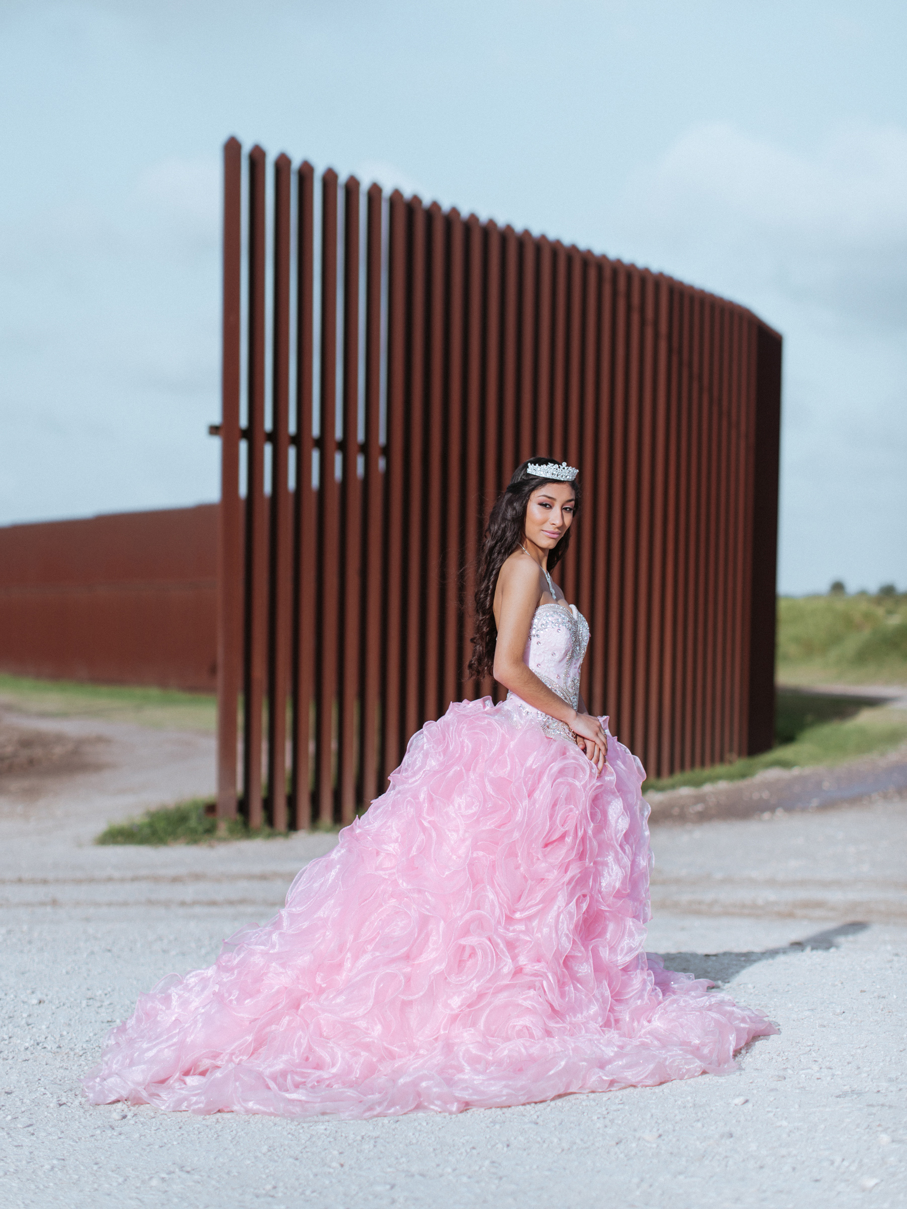 Jaymin Martinez in her quinceanera dress next to the border fence, Brownsville, Texas. (Elliot Ross)