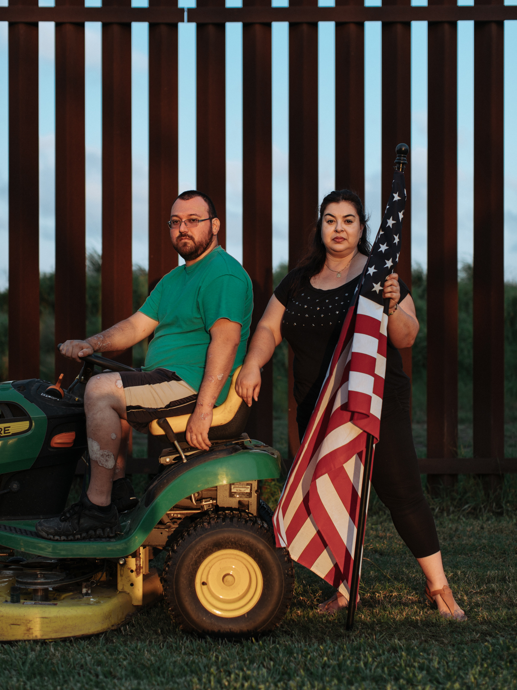 Tony and Melissa Solis stand before the border wall in their backyard, South Point, Texas. (Elliot Ross)