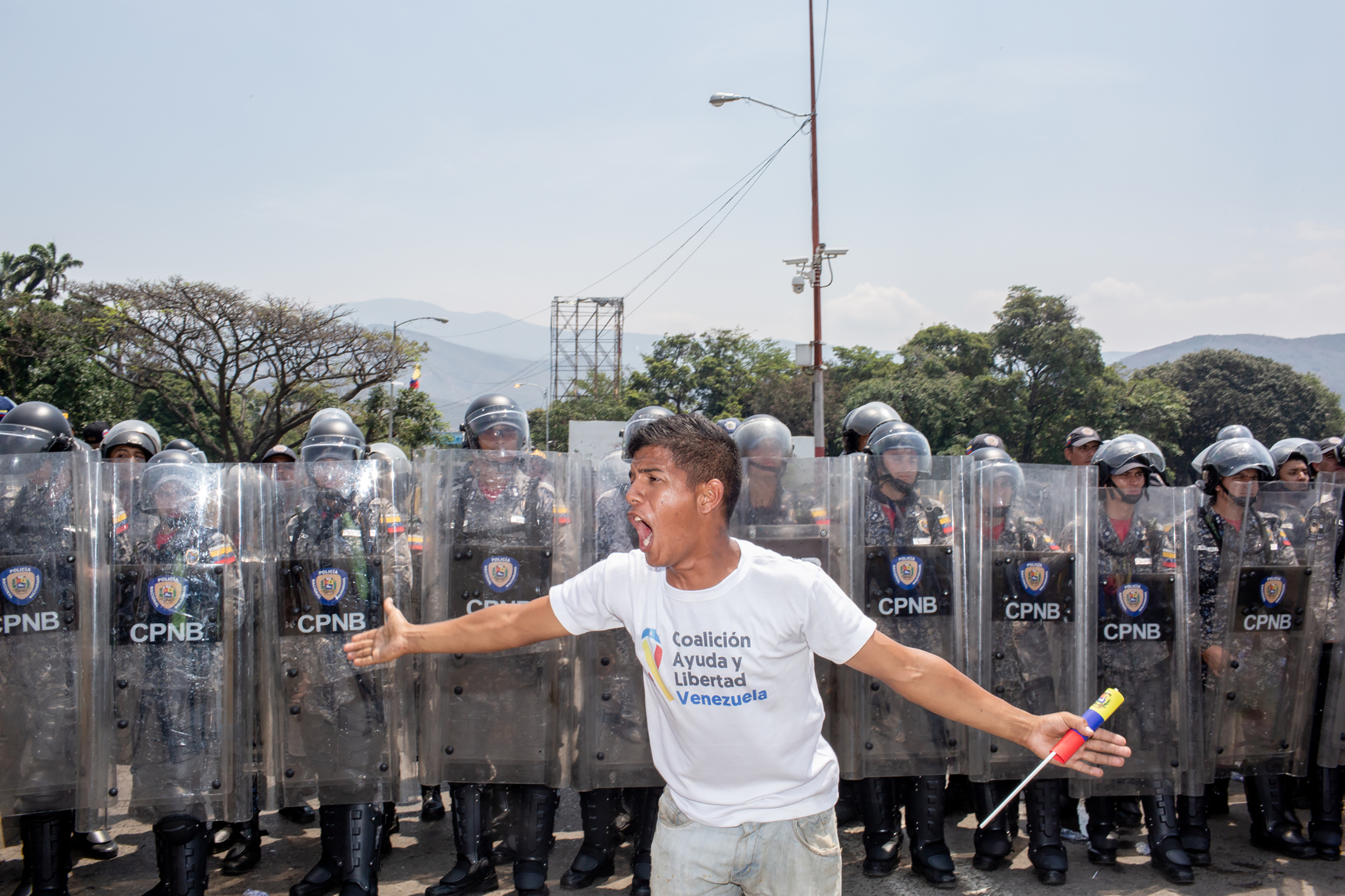 A demonstrator yells in front of Venezuelan national police officers before a clash on the bridge. (Photograph by TIME)