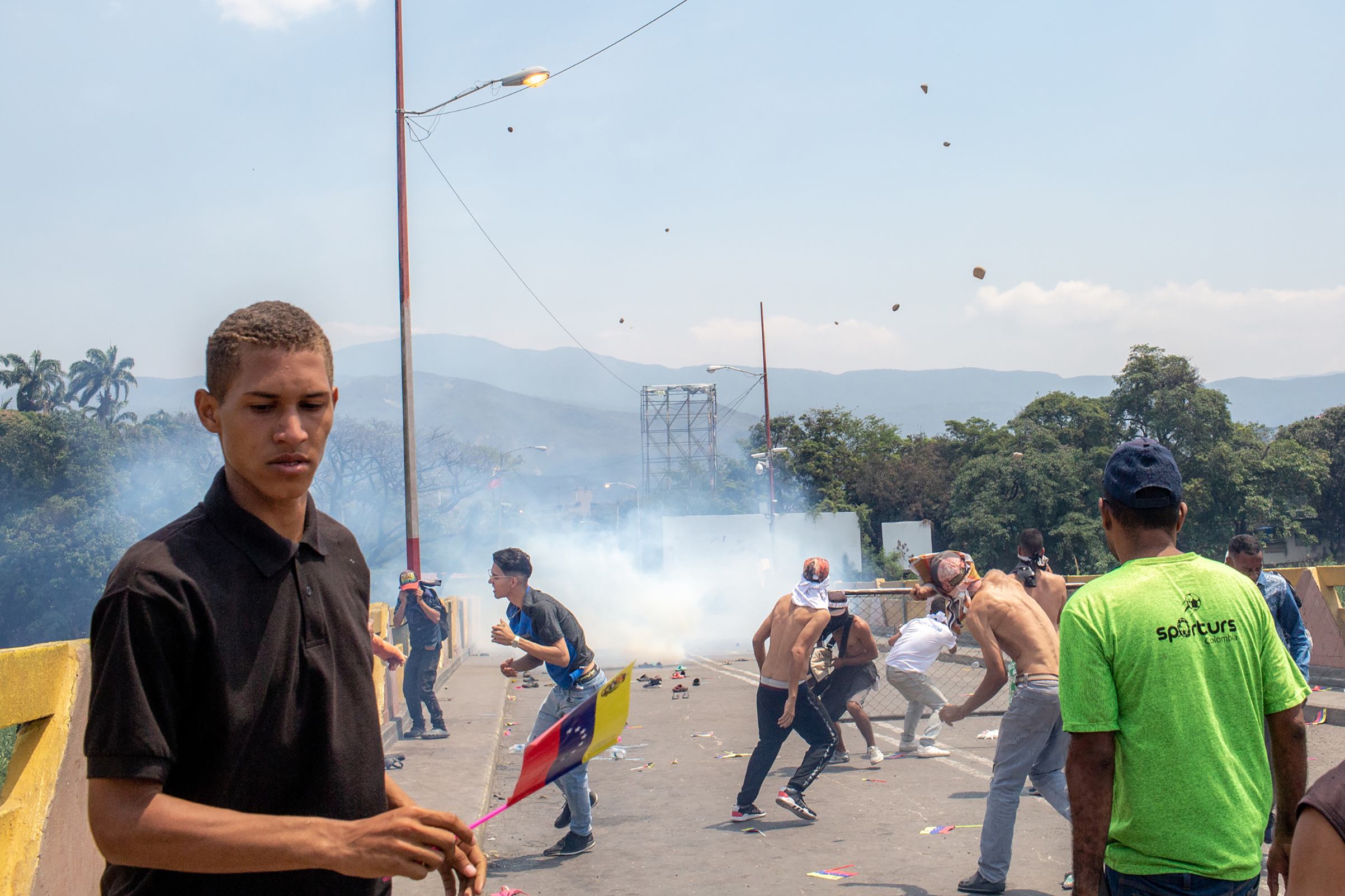 Demonstrators hurl rocks toward Venezuelan national police officers. (Photograph by TIME)