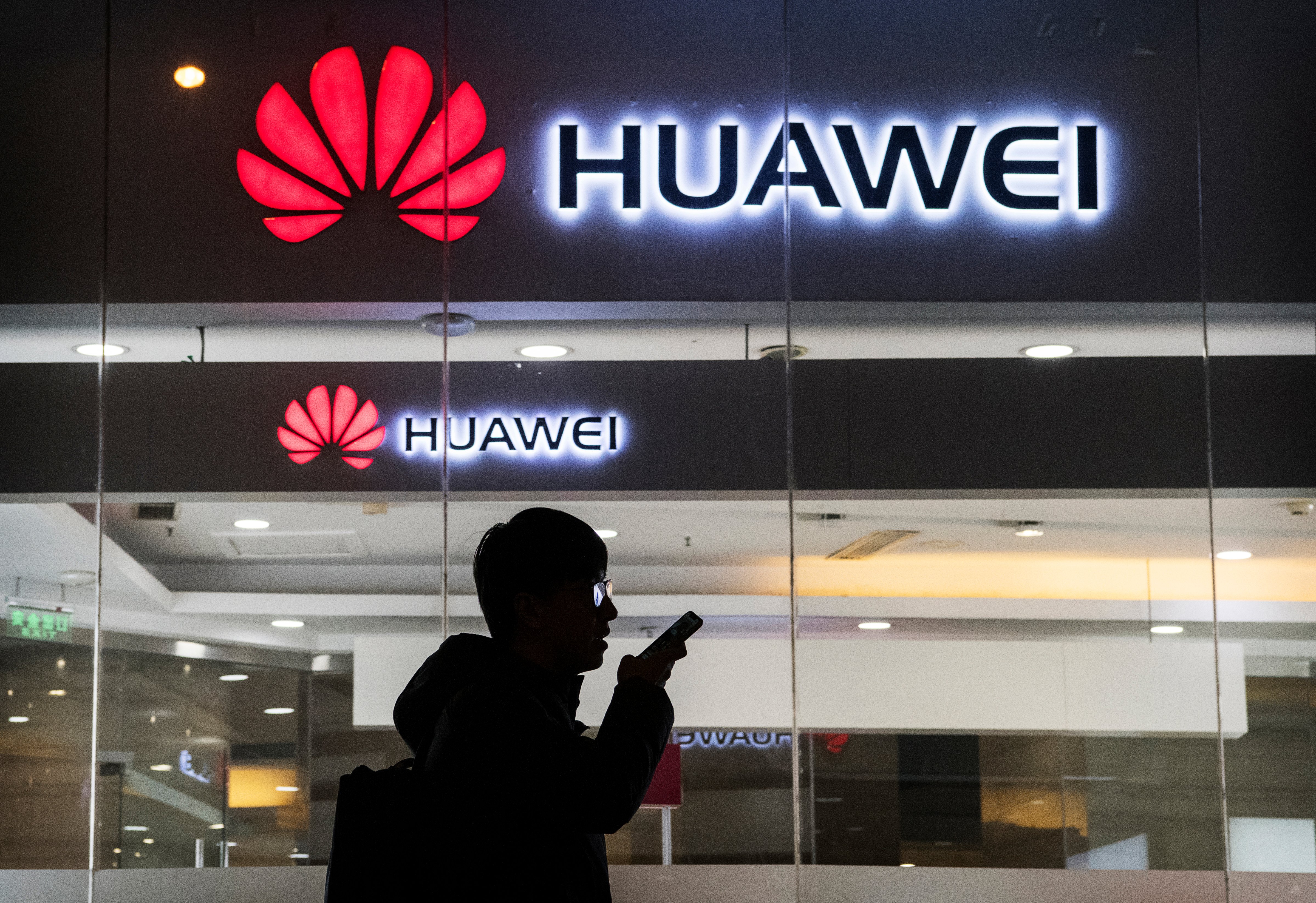 A pedestrian talks on the phone while walking past a Huawei store in Beijing on Jan. 29. (Kevin Frayer—Getty Images)