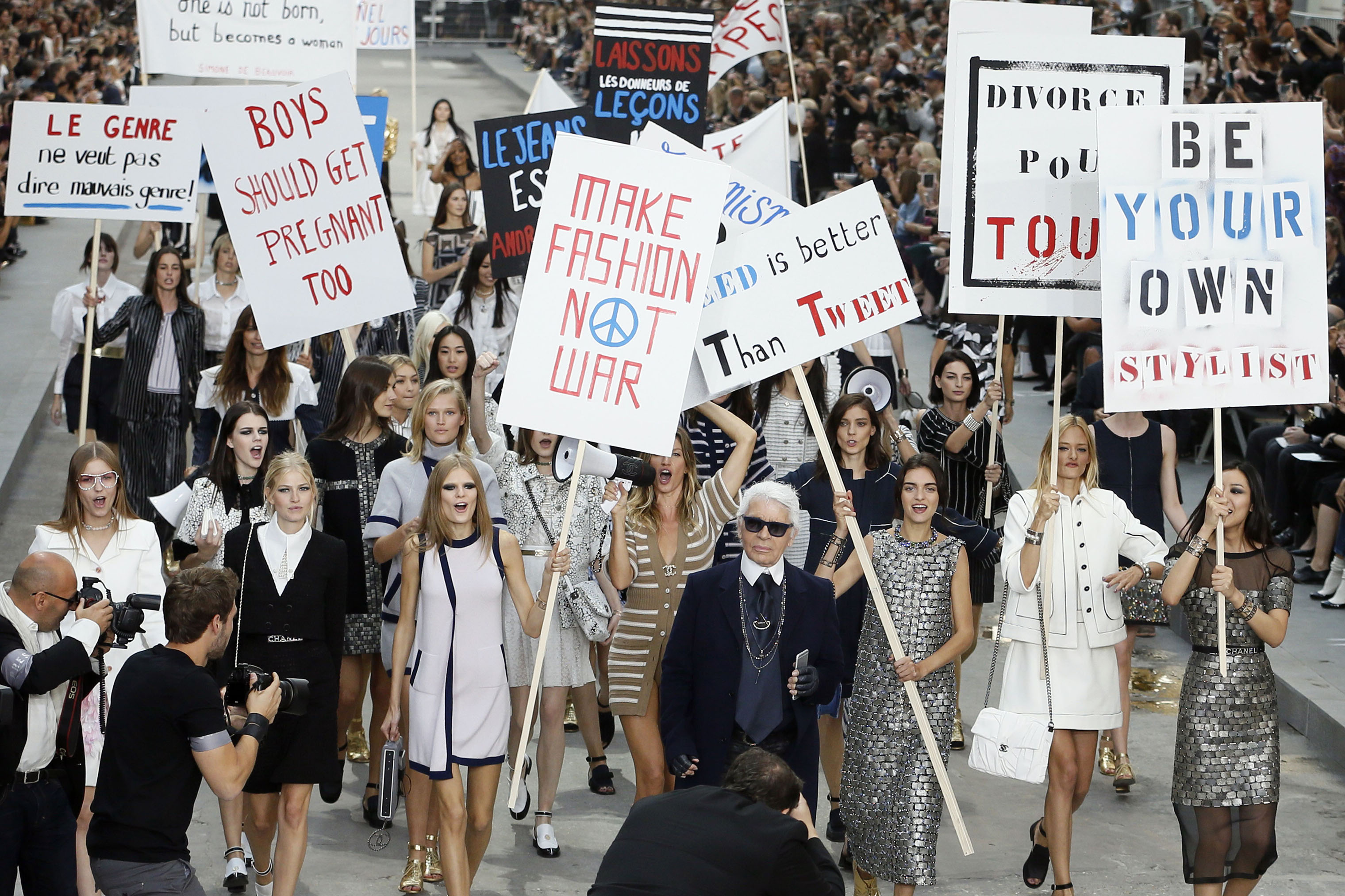 German fashion designer Karl Lagerfeld (C) acknowledges the public as Brazilian model Gisele Bundchen (back-C) speaks through a megaphone as she and other models fake a demonstration as they present creations for Chanel's 2015 Spring/Summer fashion show, on Sept. 30, 2014 at the Grand Palais in Paris. (Patrick Kovarik—AFP/Getty Images)