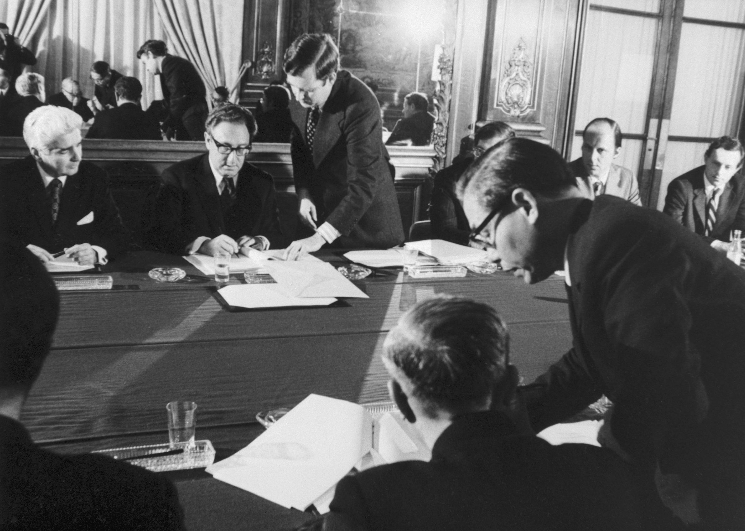 Dr. Henry Kissiinger, background, center, initialing the cease fire agreement in Paris. In the foreground Le Duc Tho affixes his signature. (Bettmann/Getty Images)