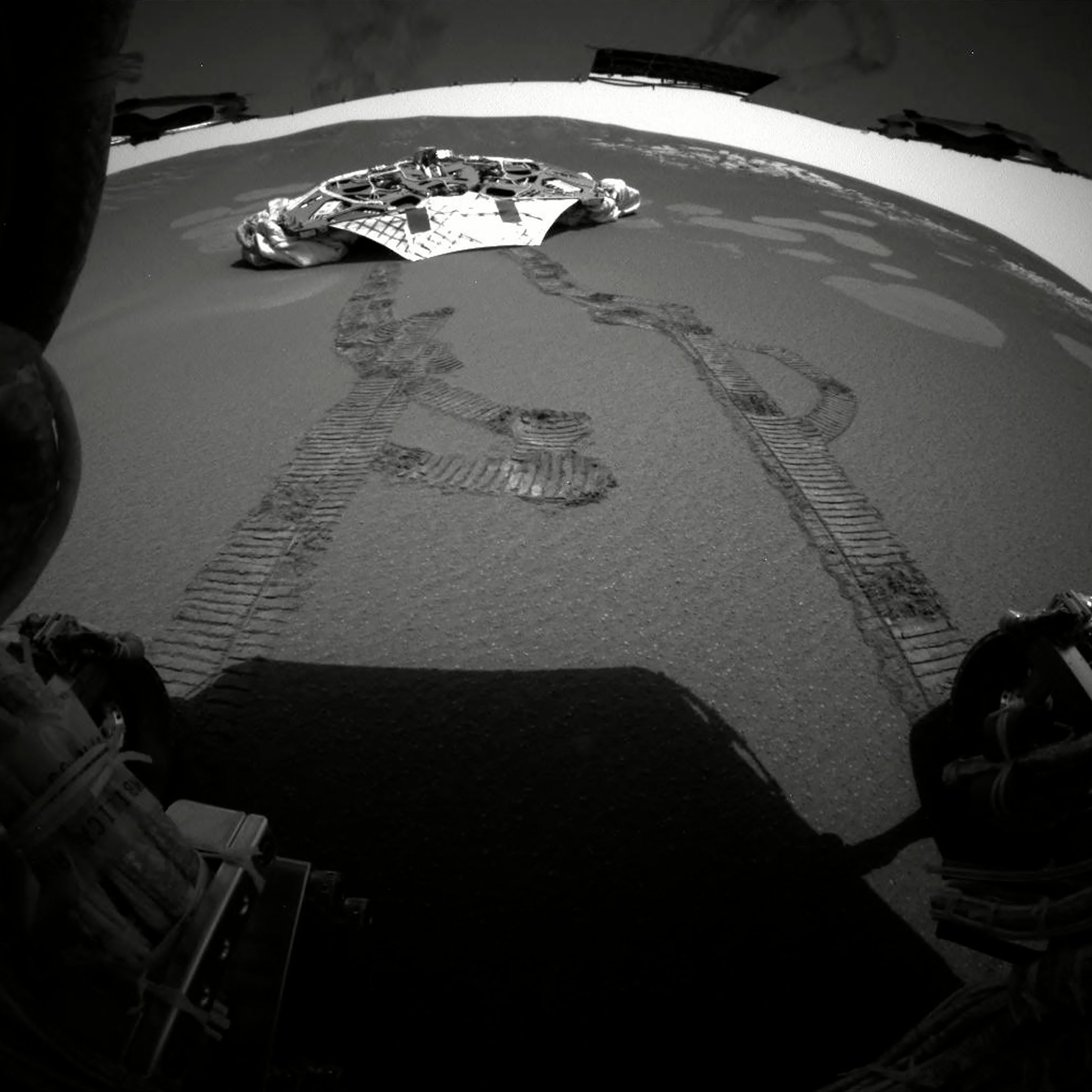 This photograph made by one of the rear hazard-avoidance cameras on Opportunity rover in February 2004 shows its landing platform, with freshly made tracks leading away from it. (AP/Shutterstock)